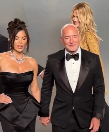 As Nicole Kidman passes behind them, Lauren Sánchez and Jeff Bezos remain hand-in-hand facing the cameras. | Source: Facebook/NewYorkPost