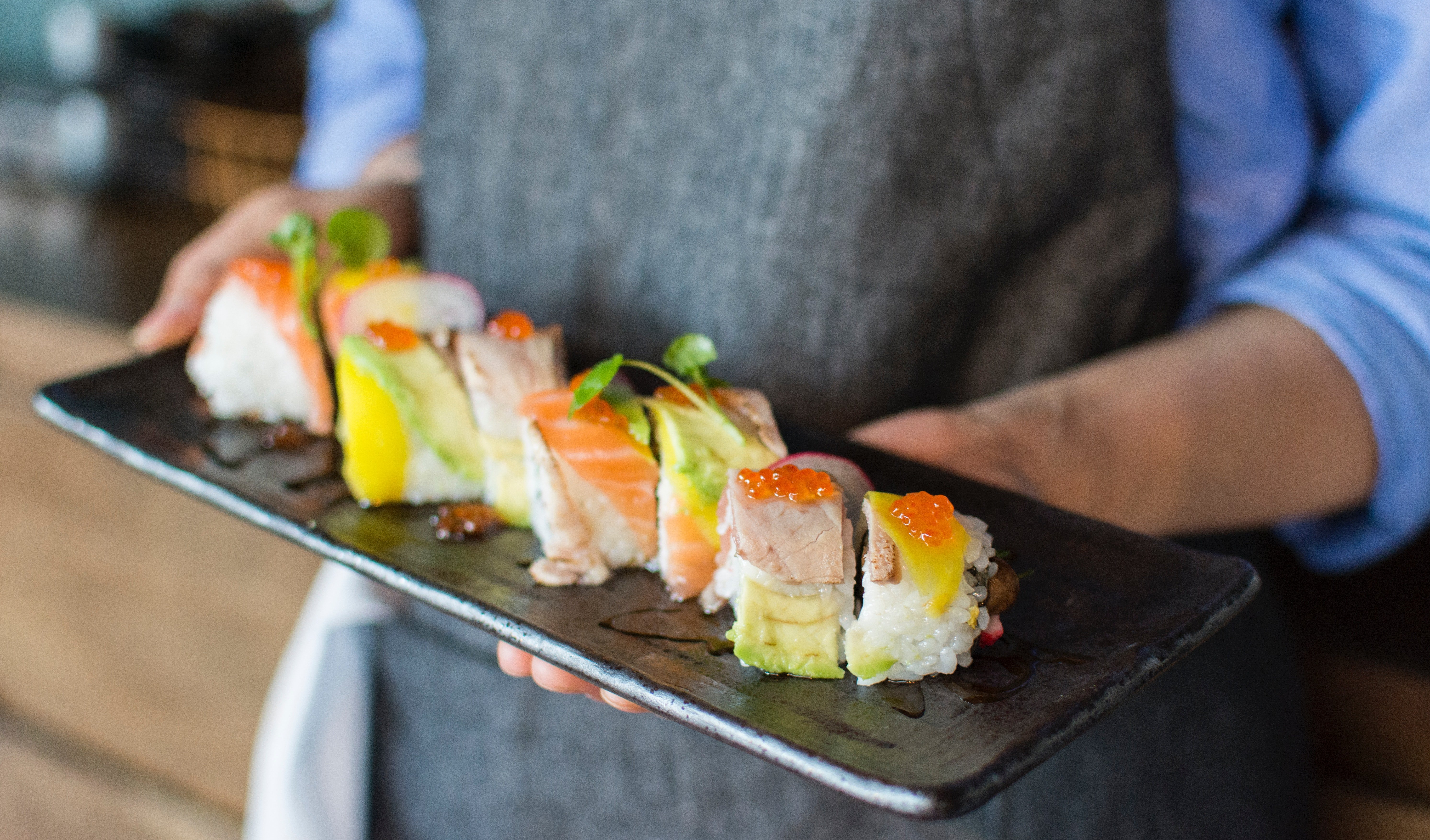 A waiter serves a platter of sushi | Photo: Pexels/Huy Phan 
