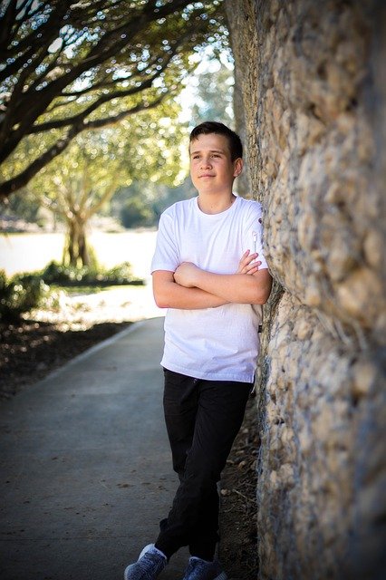 Young boy leans against a wall outside with arms folded | Photo: Pixabay