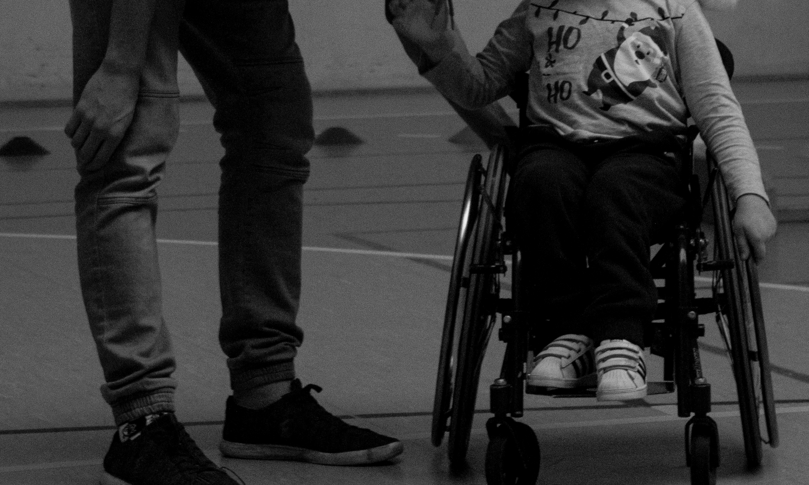 A man bends down to talk to a boy in a wheelchair | Source: Pexels