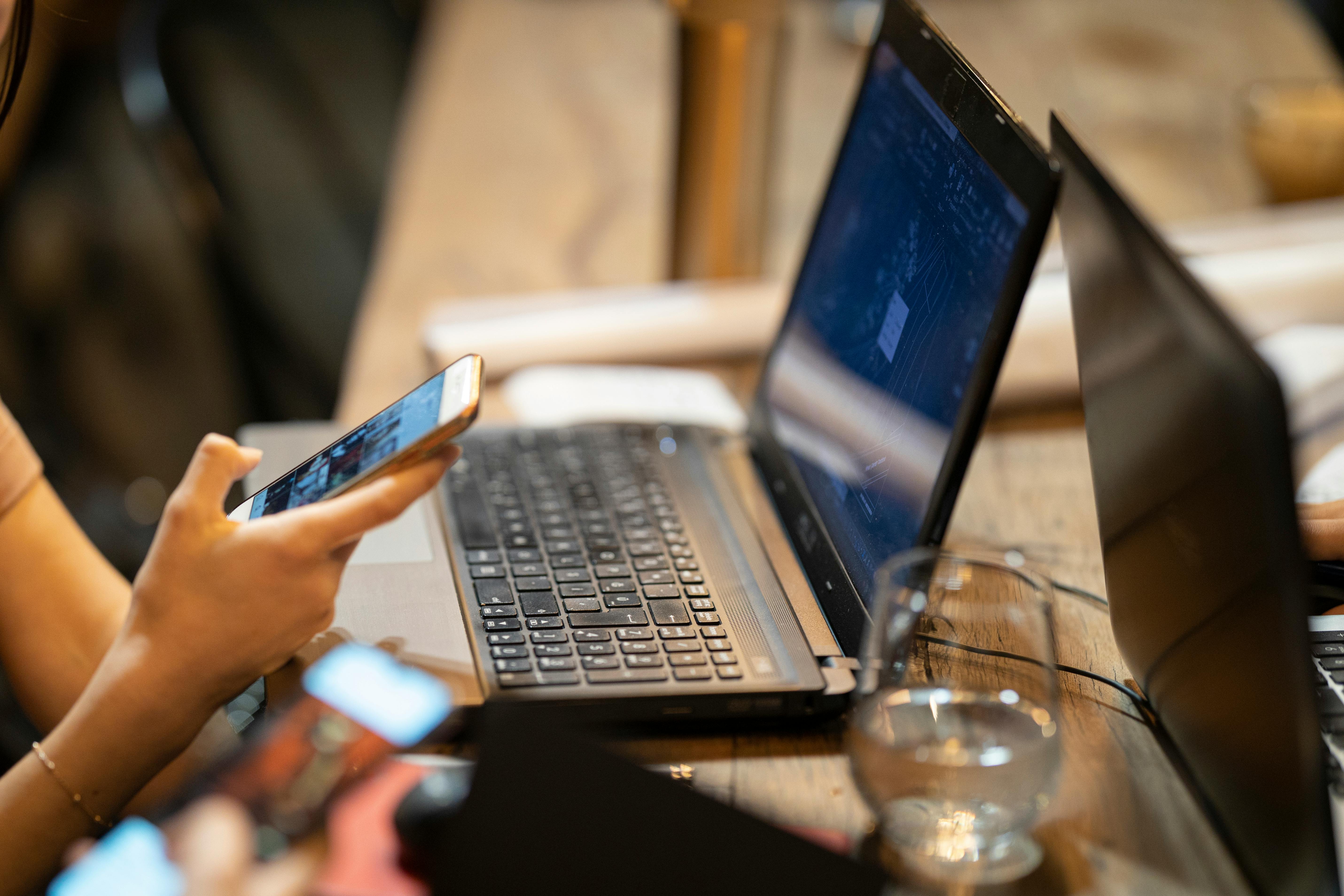 Person using phone with laptop on desk | Source: Pexels