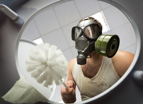 Mann mit Gasmaske reinigt Toilette | Quelle: Shutterstock
