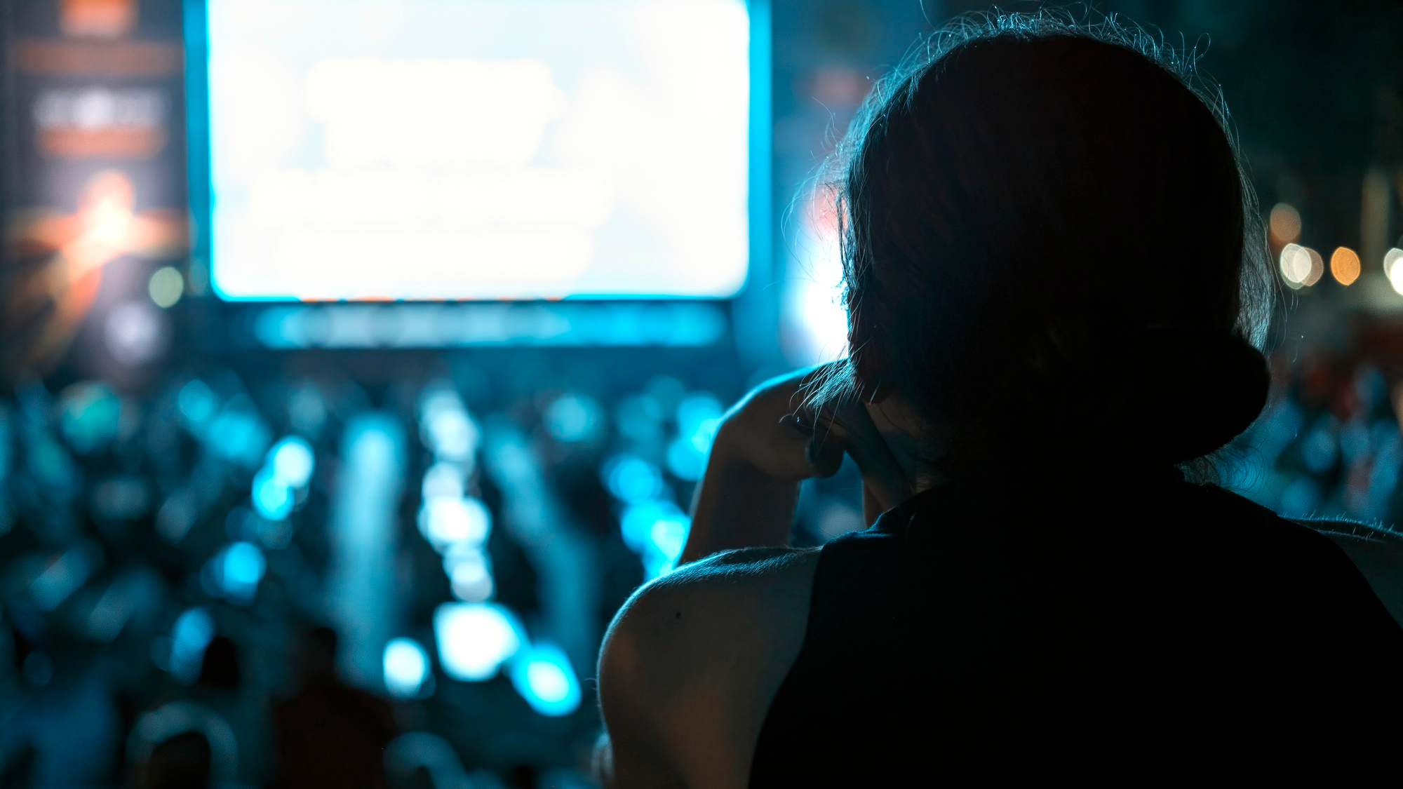 A woman watching people looking at something on a screen at an event | Source: Freepik