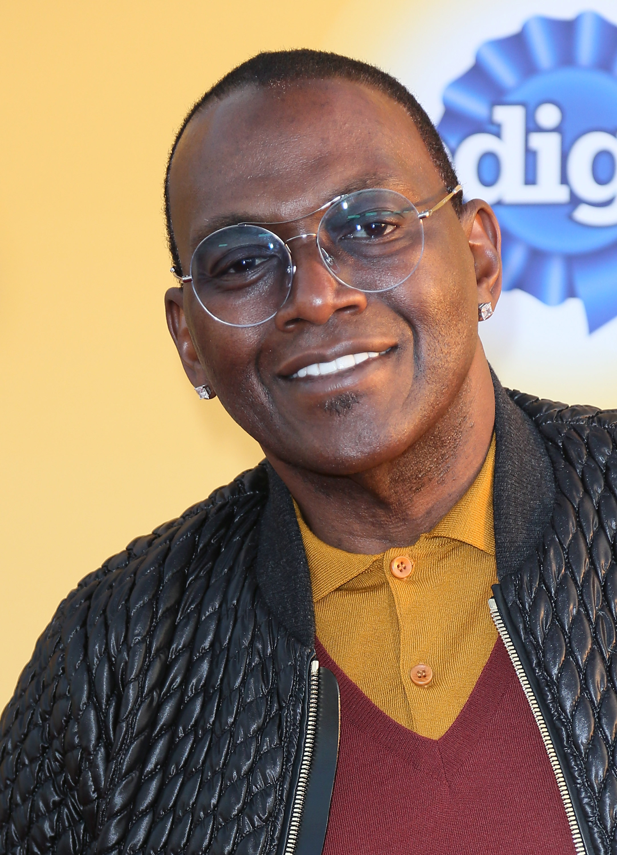 Randy Jackson sports round glasses, a quilted jacket and layered knitwear, giving a polished yet relaxed look at the star-studded dog charity event.