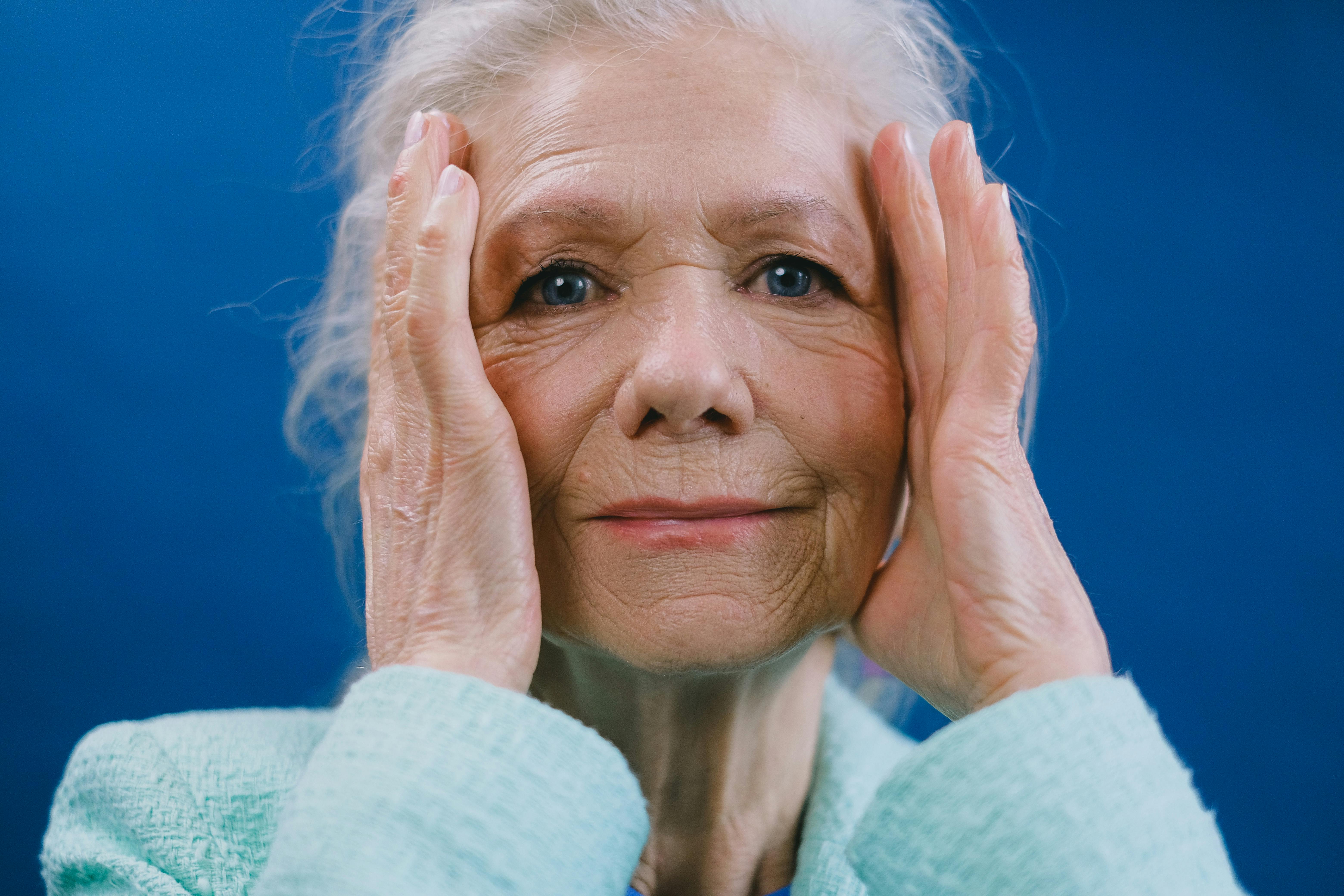 A senior woman with her hands on either side of her head | Source: Pexels