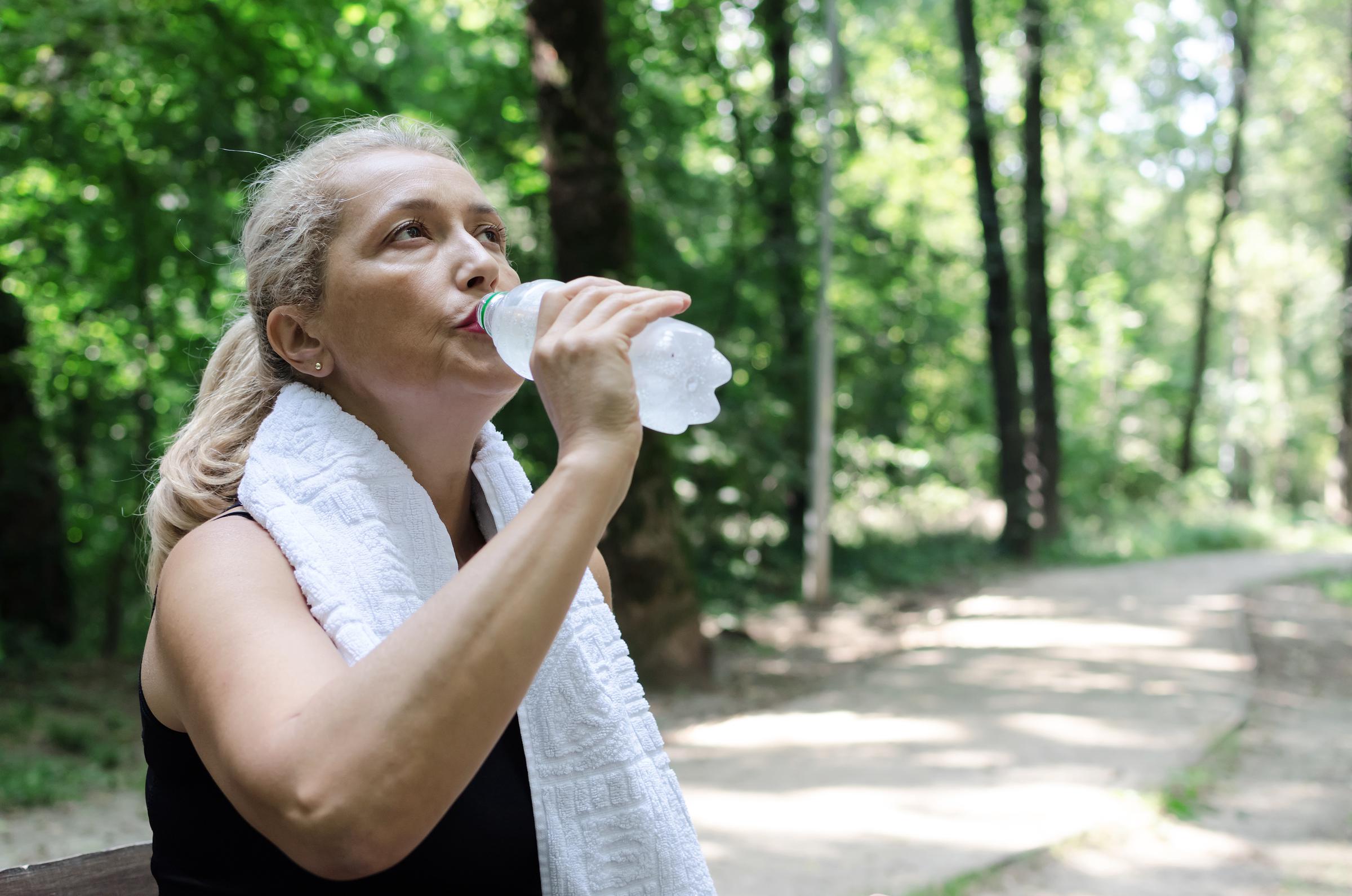 Woman taking a water break on a walking trail | Source: Shutterstock