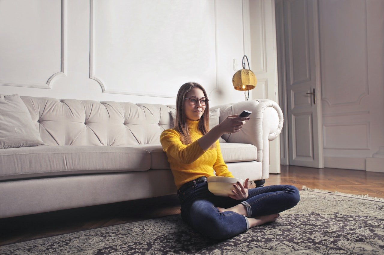 Mujer con el control del televisor en la mano. | Foto: Pexels