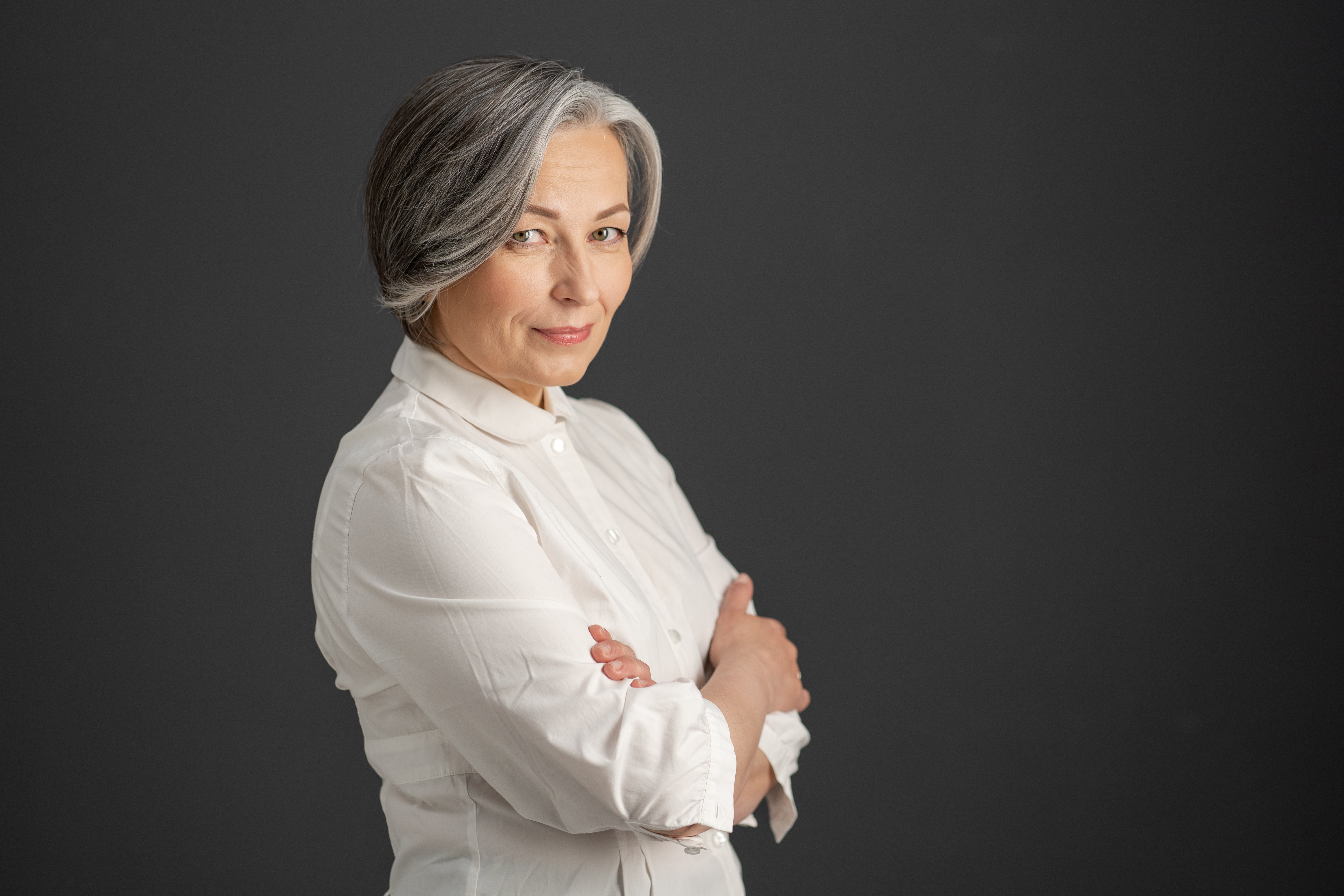 Une jolie femme aux cheveux blancs sourit. | Photo : shutterstock