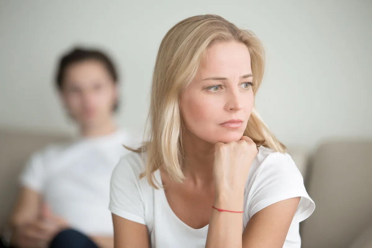 Eine Frau sieht wütend aus, während hinter ihr ein Mann sitzt. | Source: Shutterstock