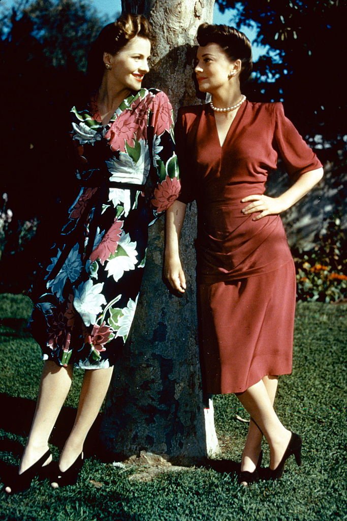 Full-length portrait of Joan Fontaine (left) and her sister, Olivia de Havilland, both British actress, standing in conversation by a tree, circa 1945. | Source: Getty Images