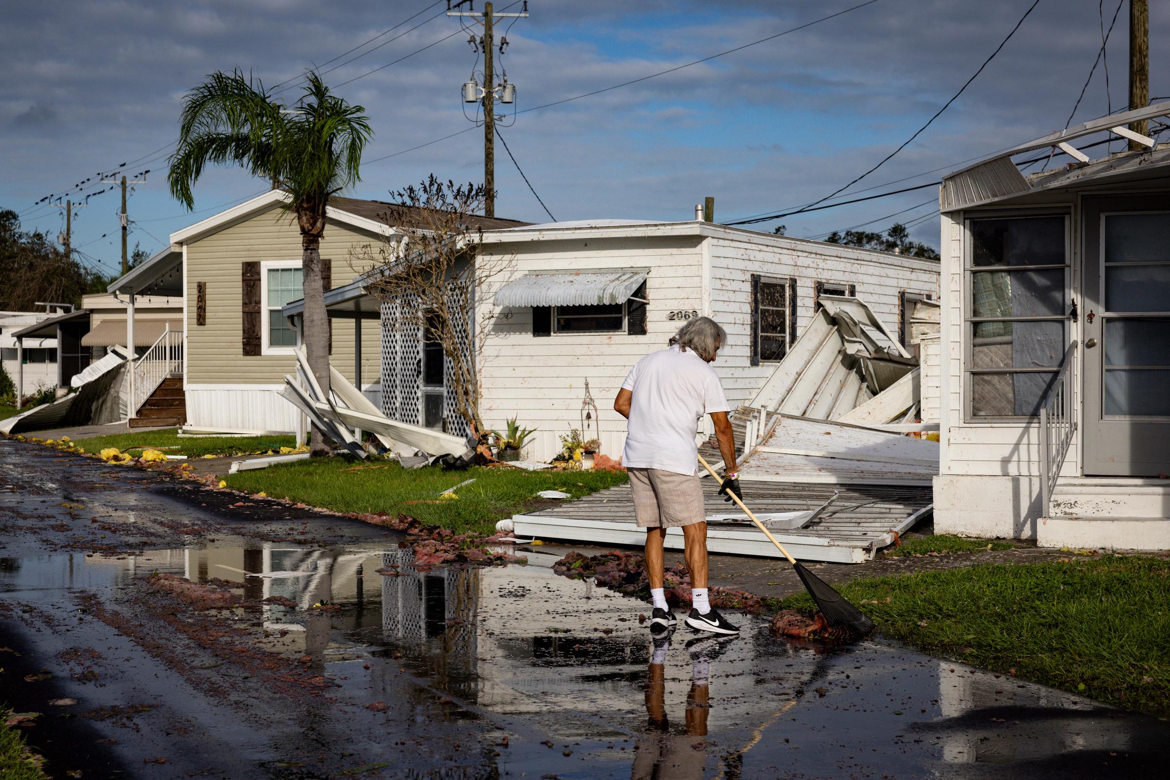 A resident of Sarasota, Florida cleans the front of his mobile home after Hurricane Milton's landfall on October 10, 2024 | Source: Getty Images