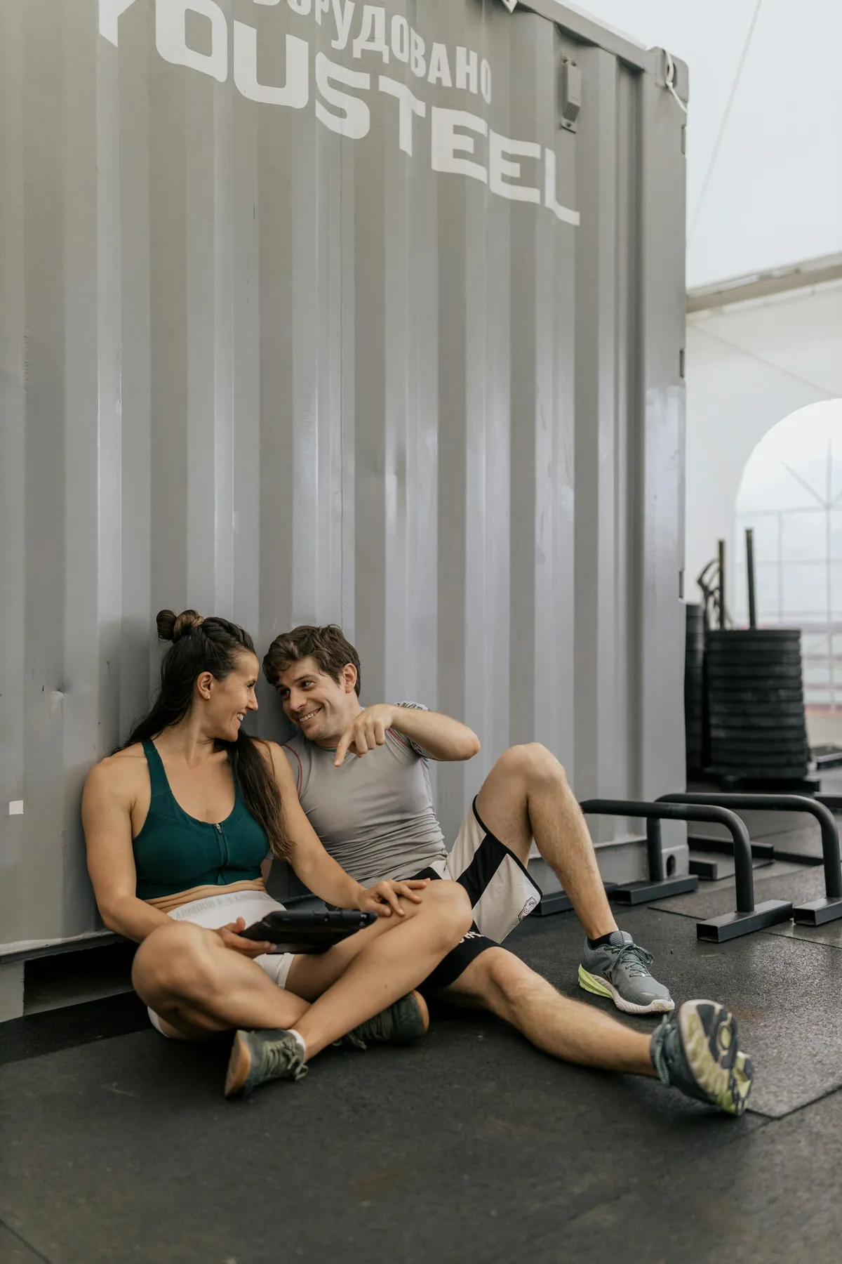 Una pareja en ropa deportiva sentada en el suelo y charlando | Fuente: Pexels