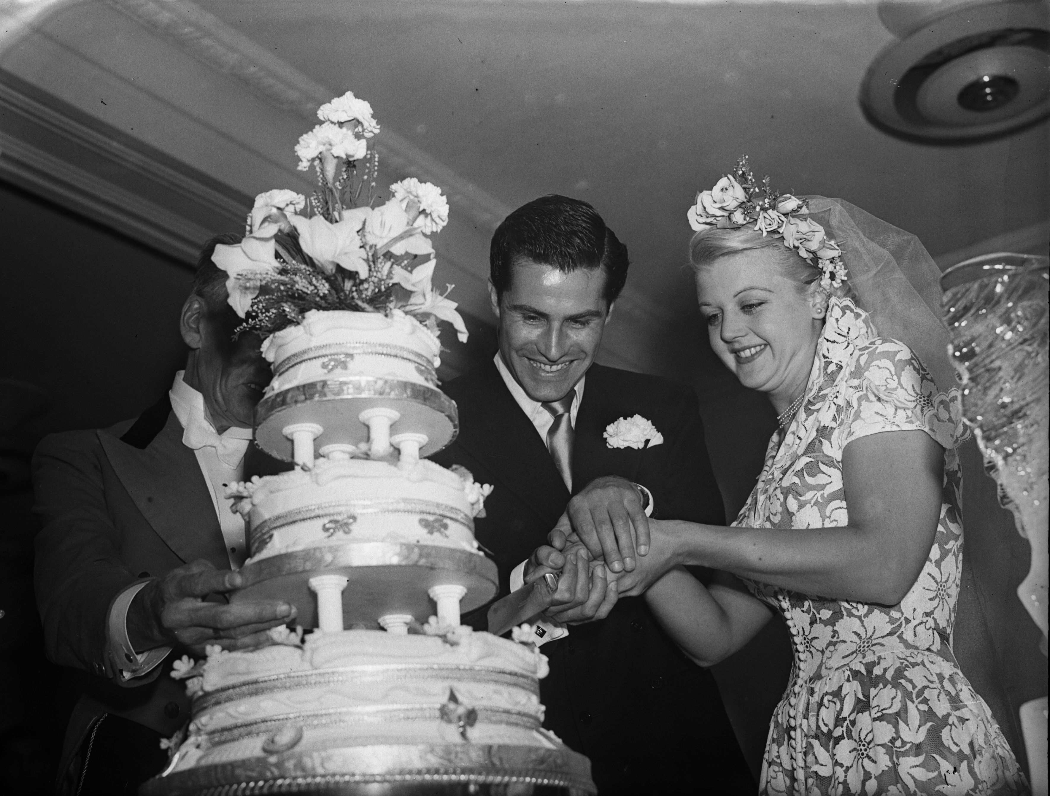 La actriz británica Angela Lansbury y su esposo, Peter Shaw, cortando el pastel en su boda. | Foto: Getty Images