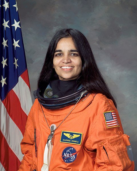 Portrait of Kalpana Chawla in NASA uniform with U.S. flag in the background | Source: Wikimedia Commons