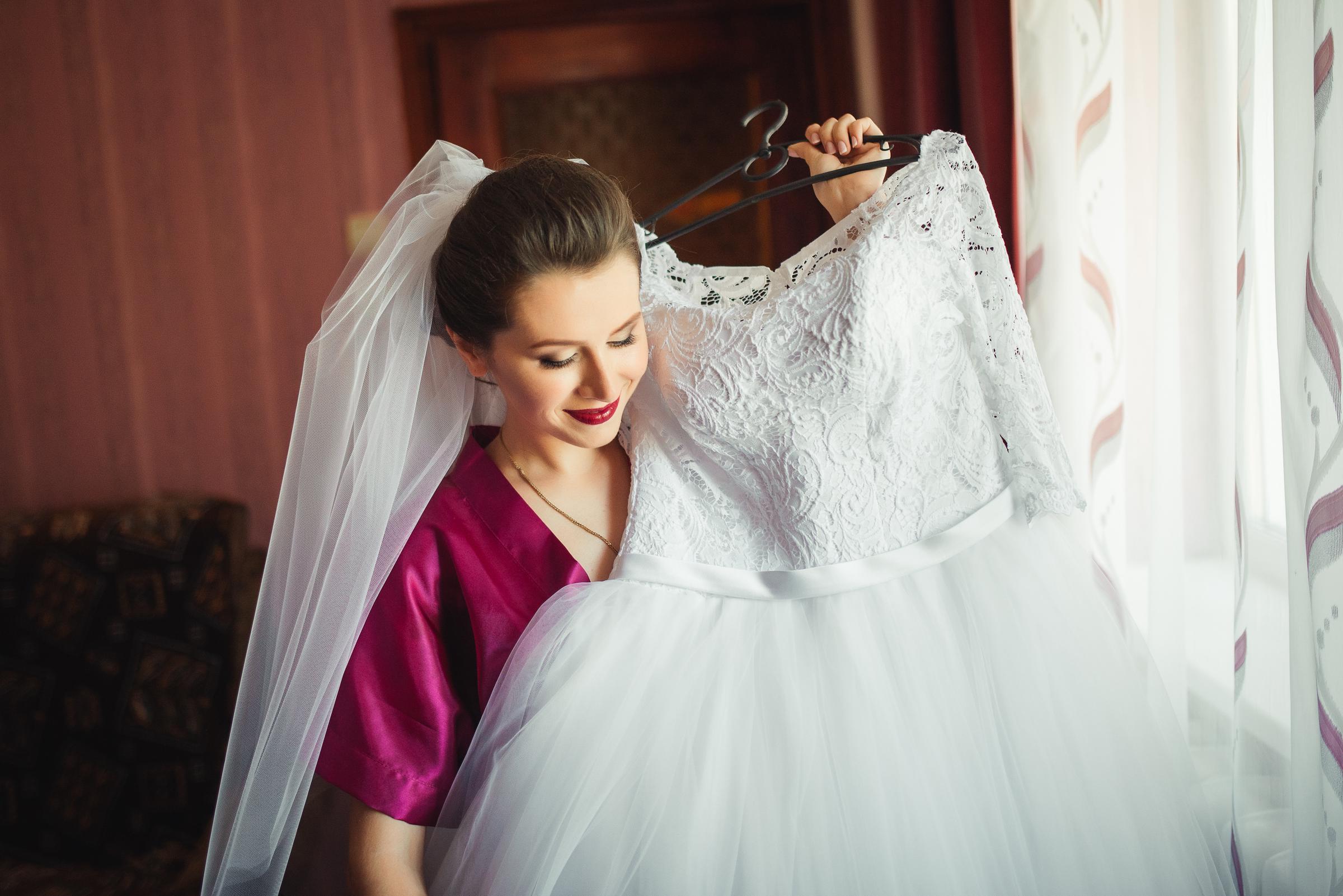 A cheerful woman holding a bridal gown | Source: Freepik