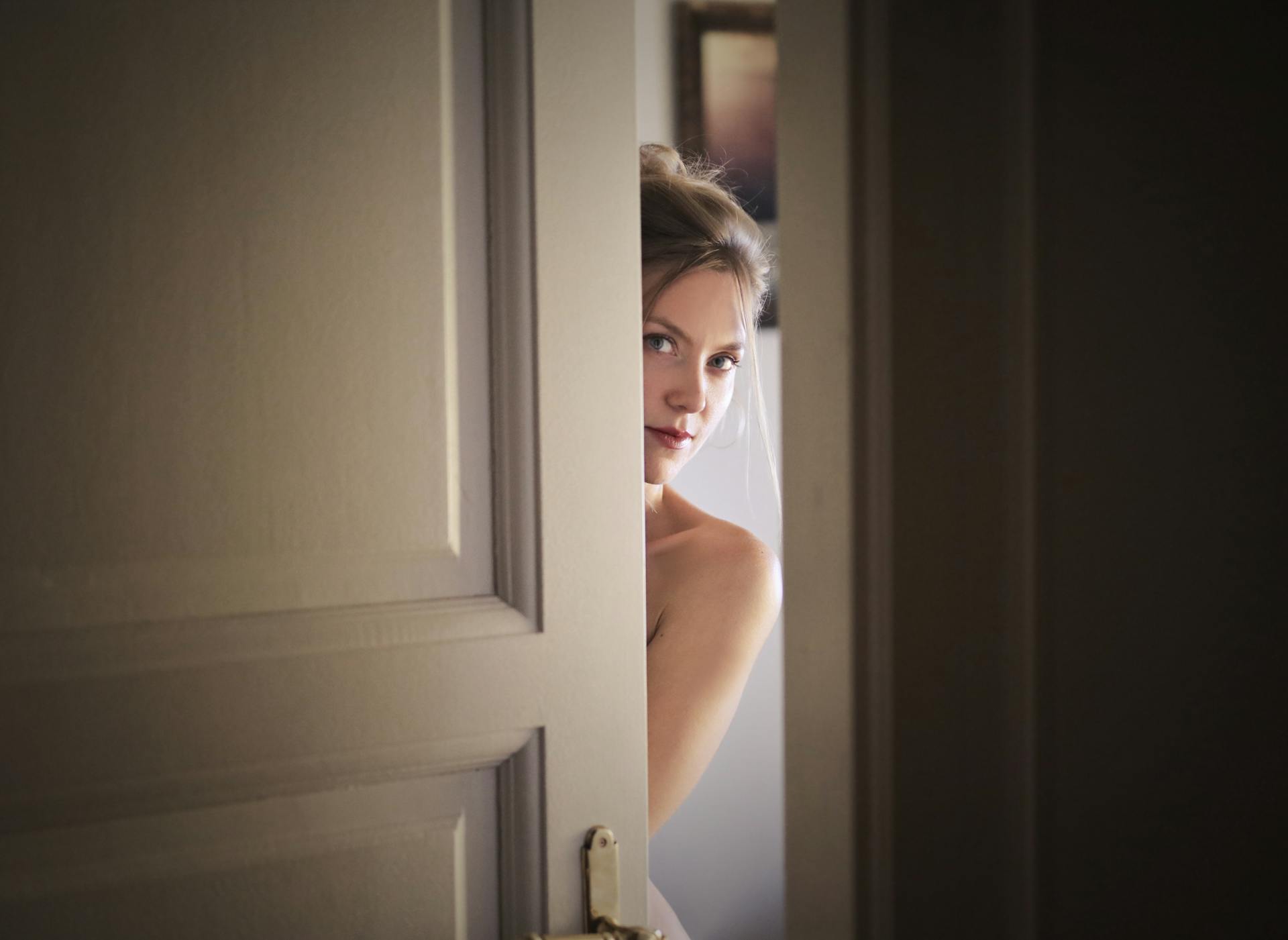 A woman peeking around a door | Source: Pexels