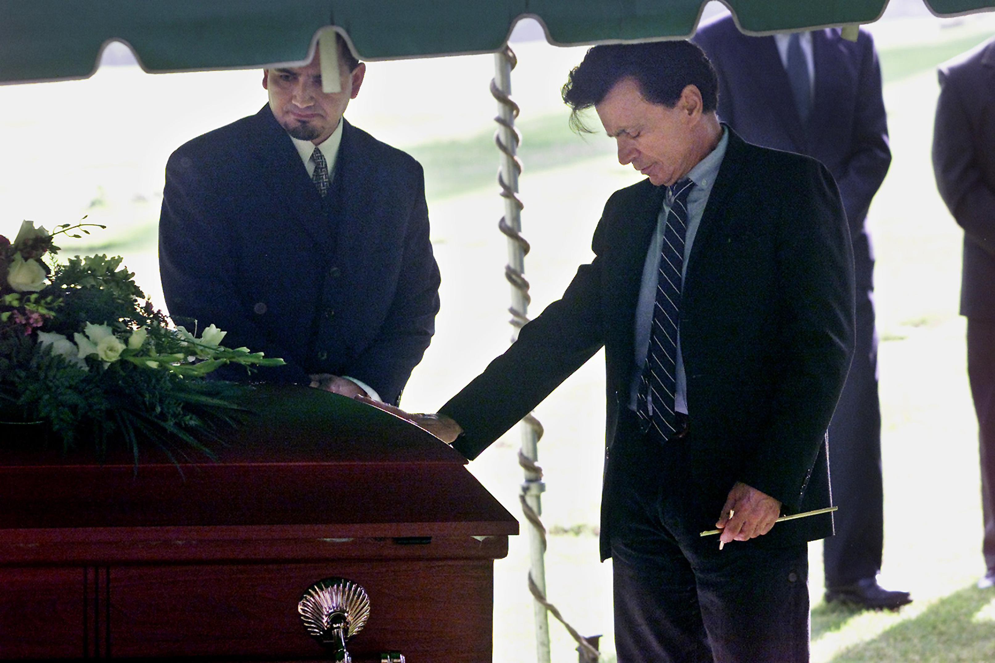 Robert Blake places a hand on the coffin of his wife, Bonny Lee Bakley, during a brief funeral ceremony on May 25, 2001, in Los Angeles, California | Source: Getty Images