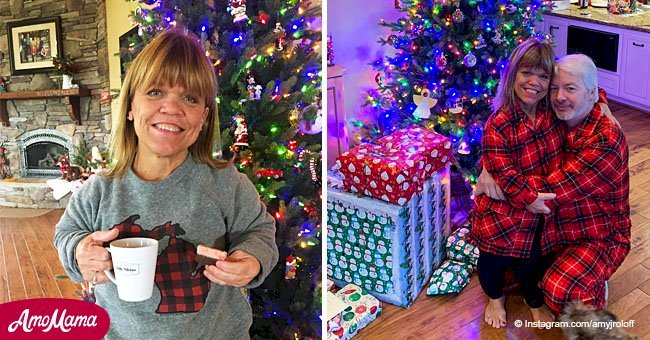 Amy Roloff hugs her boyfriend wearing matching pajamas posing under a sparkling Christmas tree