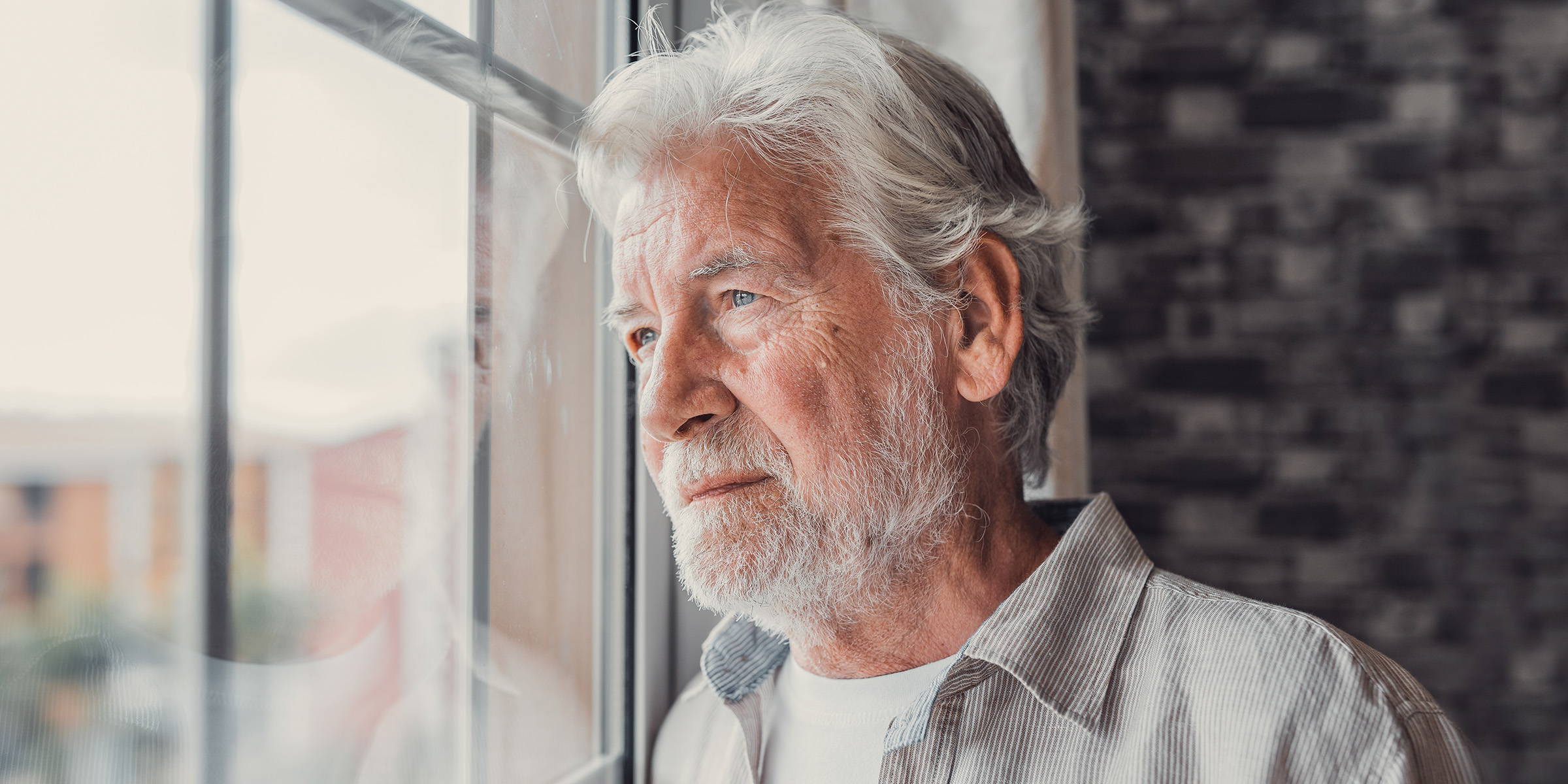An elderly man standing thoughtfully at a window | Source: Amomama