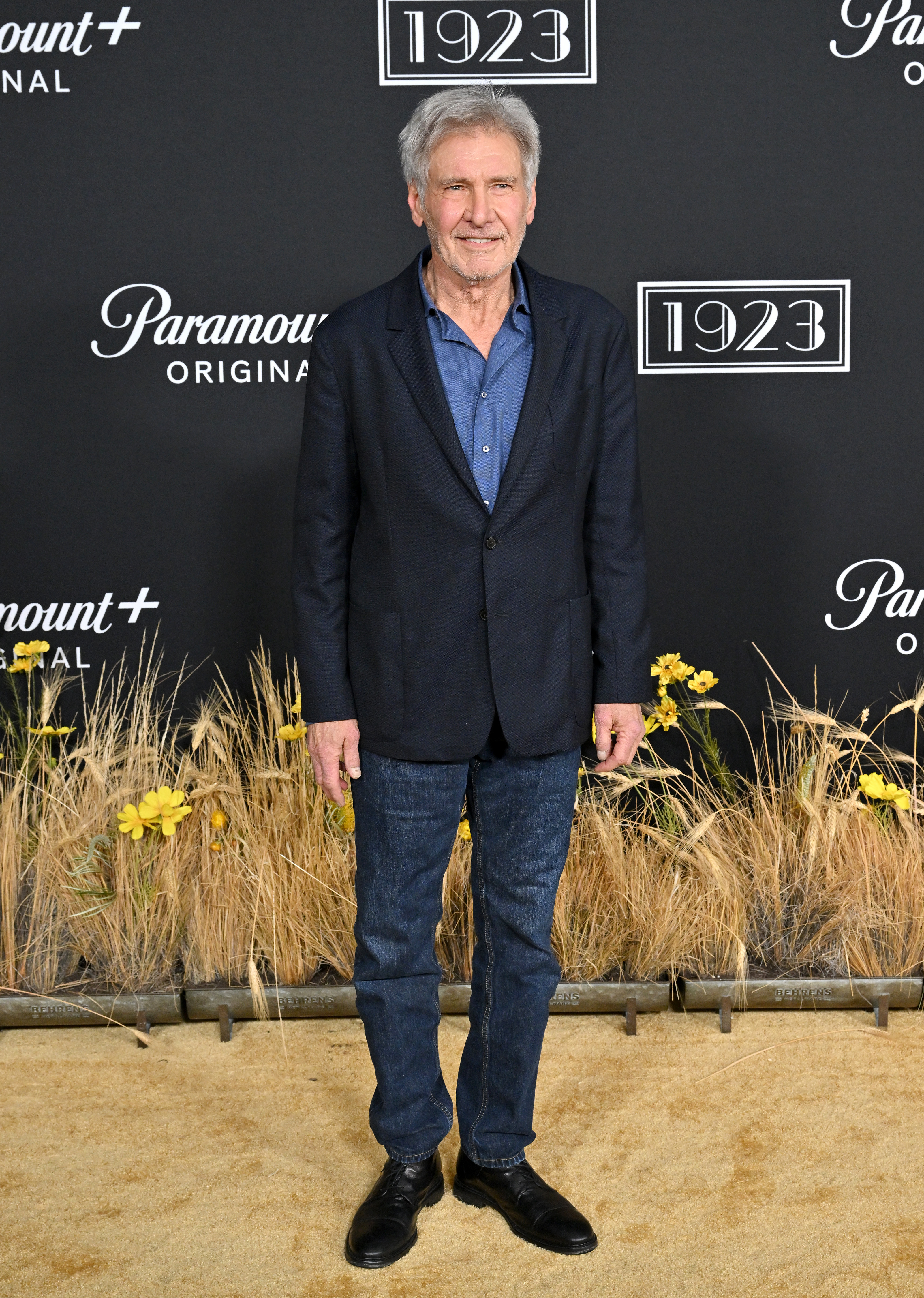 Harrison Ford keeps things relaxed yet refined at the Hollywood American Legion while attending the Los Angeles premiere of his Western drama series, "1923." The actor paired a tailored charcoal sport coat with an open-collared blue button-down shirt and classic dark jeans. | Source: Getty Images