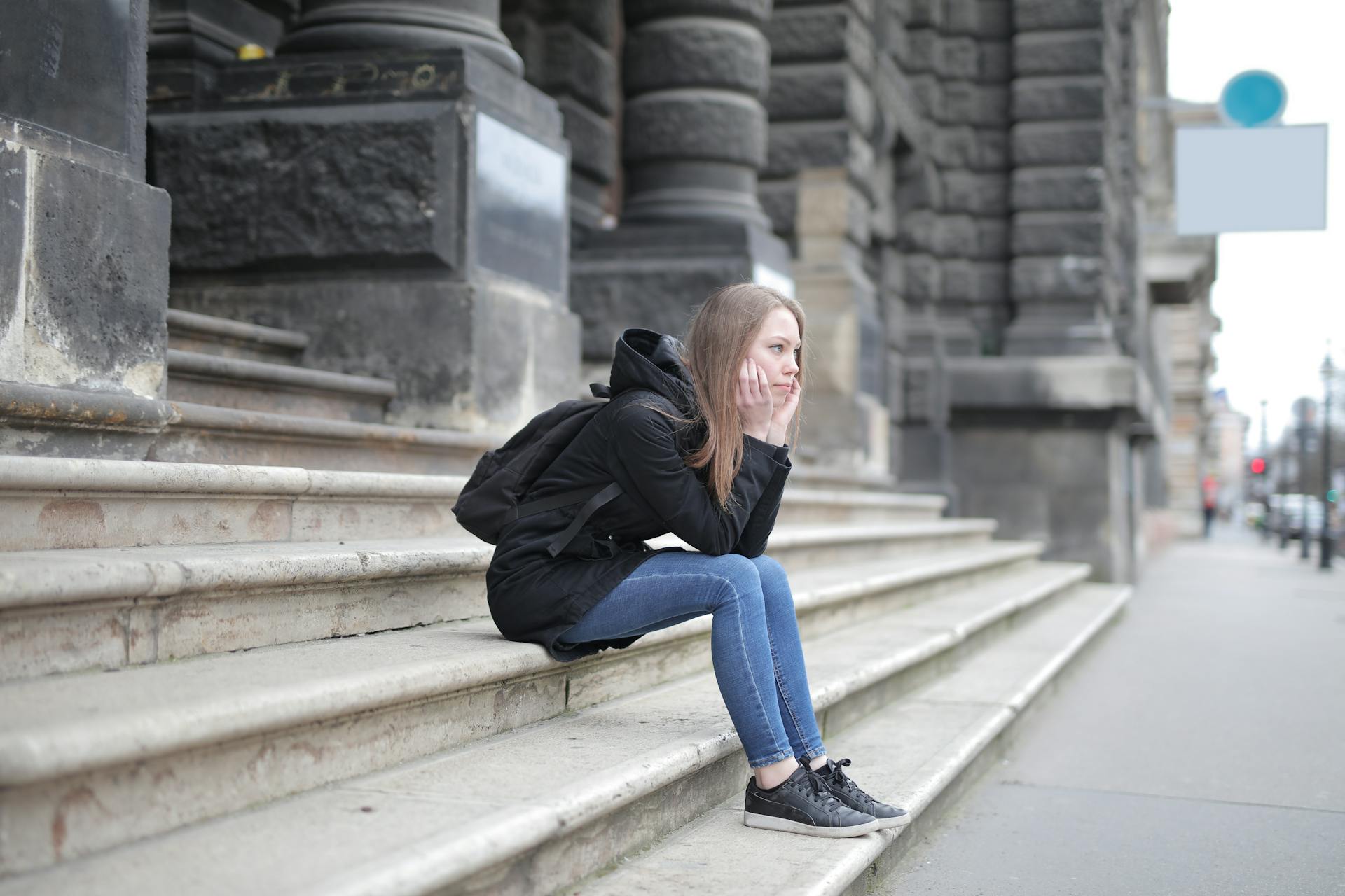 A thoughtful young woman sitting on the stairs of an antique building | Source: Pexels