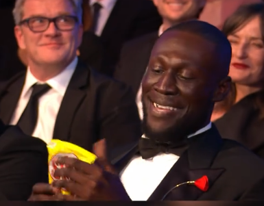 Britsih Rapper Stormzy receiving a snack from Alan Cumming at the 79th BAFTA Film Awards dated February 22, 2026 | Source: TikTok/bbc