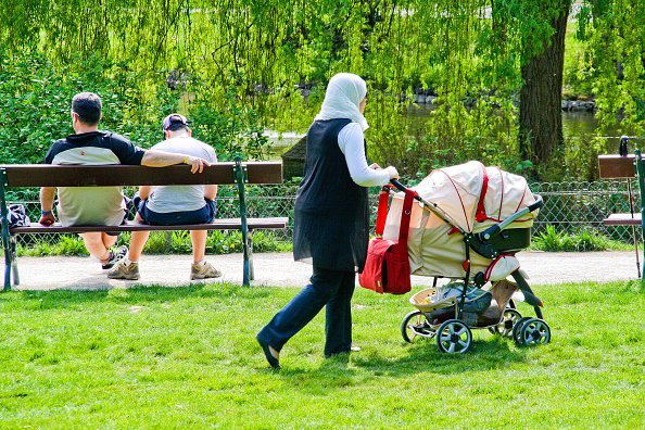Femme avec foulard sur sa tete roule une poussette sur la pelouse du Jardin des Plantes.| Photo : Getty Images