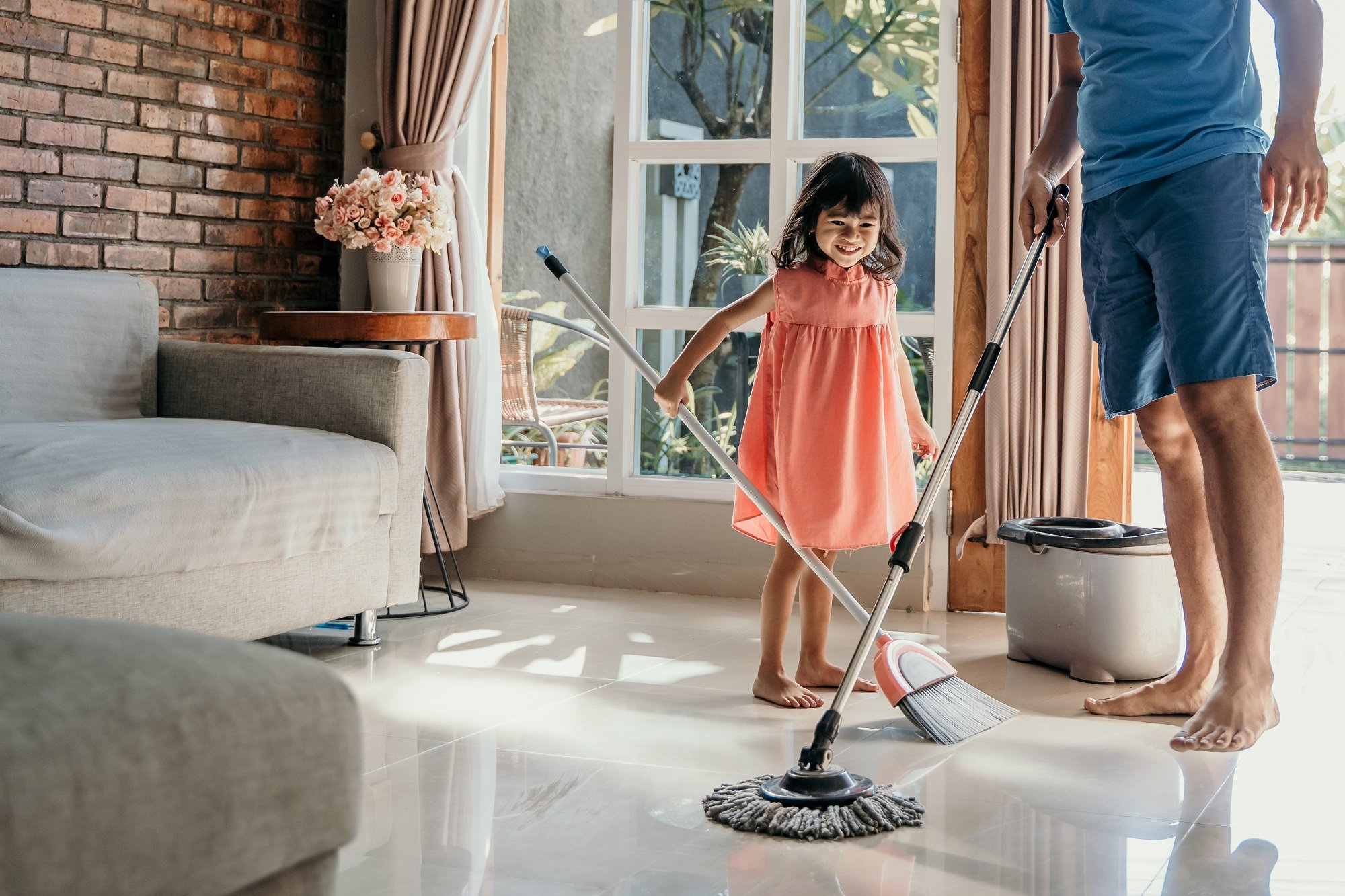 Padre e hija barren y trapean el piso juntos. | Foto: Shutterstock