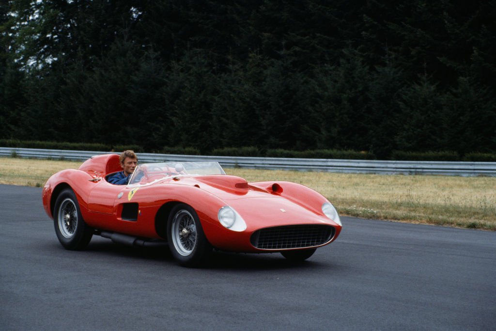 Le chanteur et acteur français Johnny Hallyday au volant d'une Ferrari 250 GT Testarossa décapotable rouge. | Photo : Getty Images