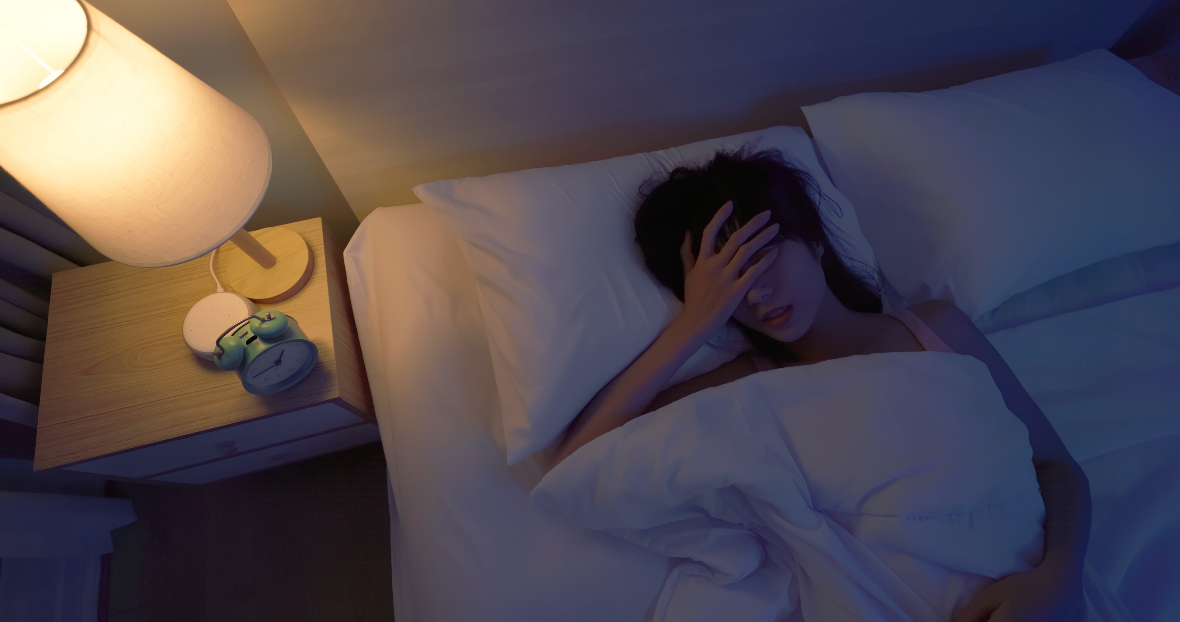 Woman laying in bed holding her head, seemingly in pain | Source: Getty Images