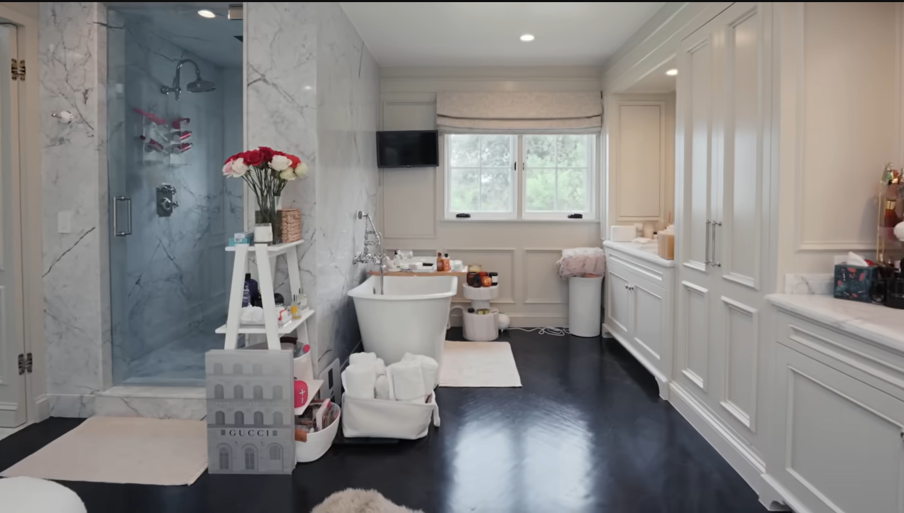 Sprawling and gorgeous! Palmer's marble-clad bathroom sanctuary features a flat-screen TV to provide her favorite ambient noise while turning down. | Source: YouTube/@Archdigest