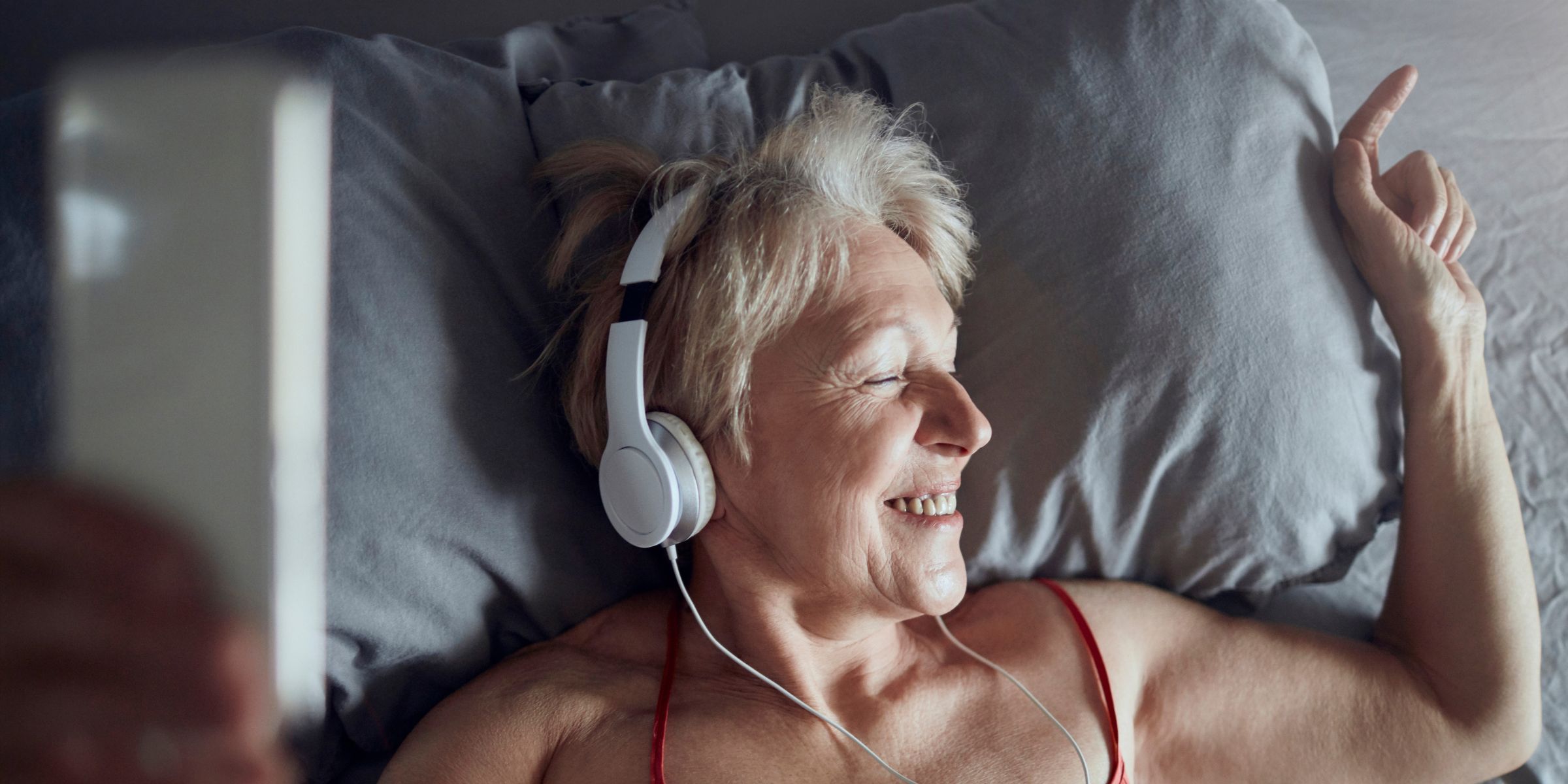 Woman enjoying some music in bed | Source: Shutterstock