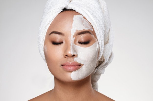Mujer con medio rostro cubierto de crema cosmética. │Foto: Freepik