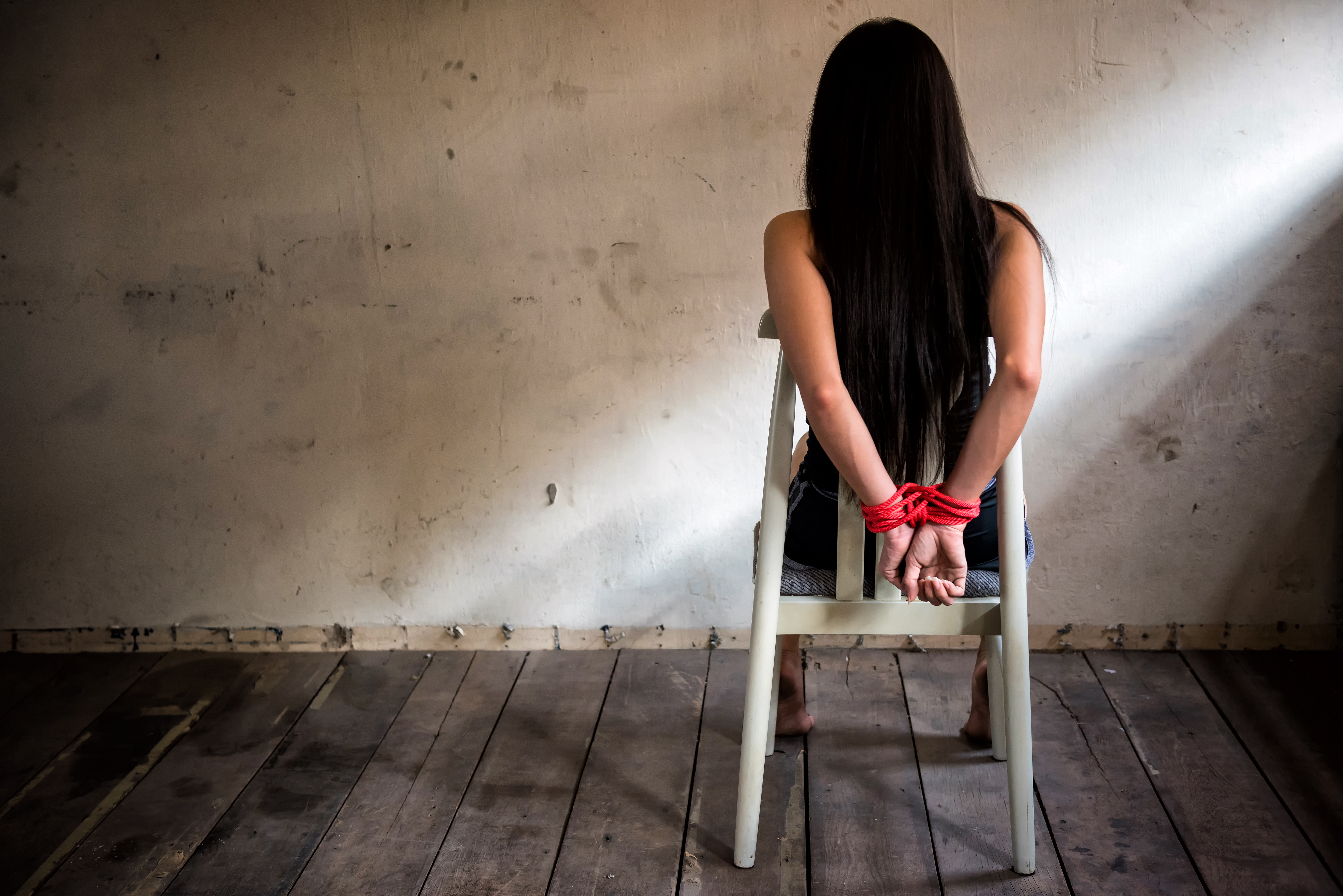 Victim woman tied with red rope sit on chair in abandon house | Source: Shutterstock.com