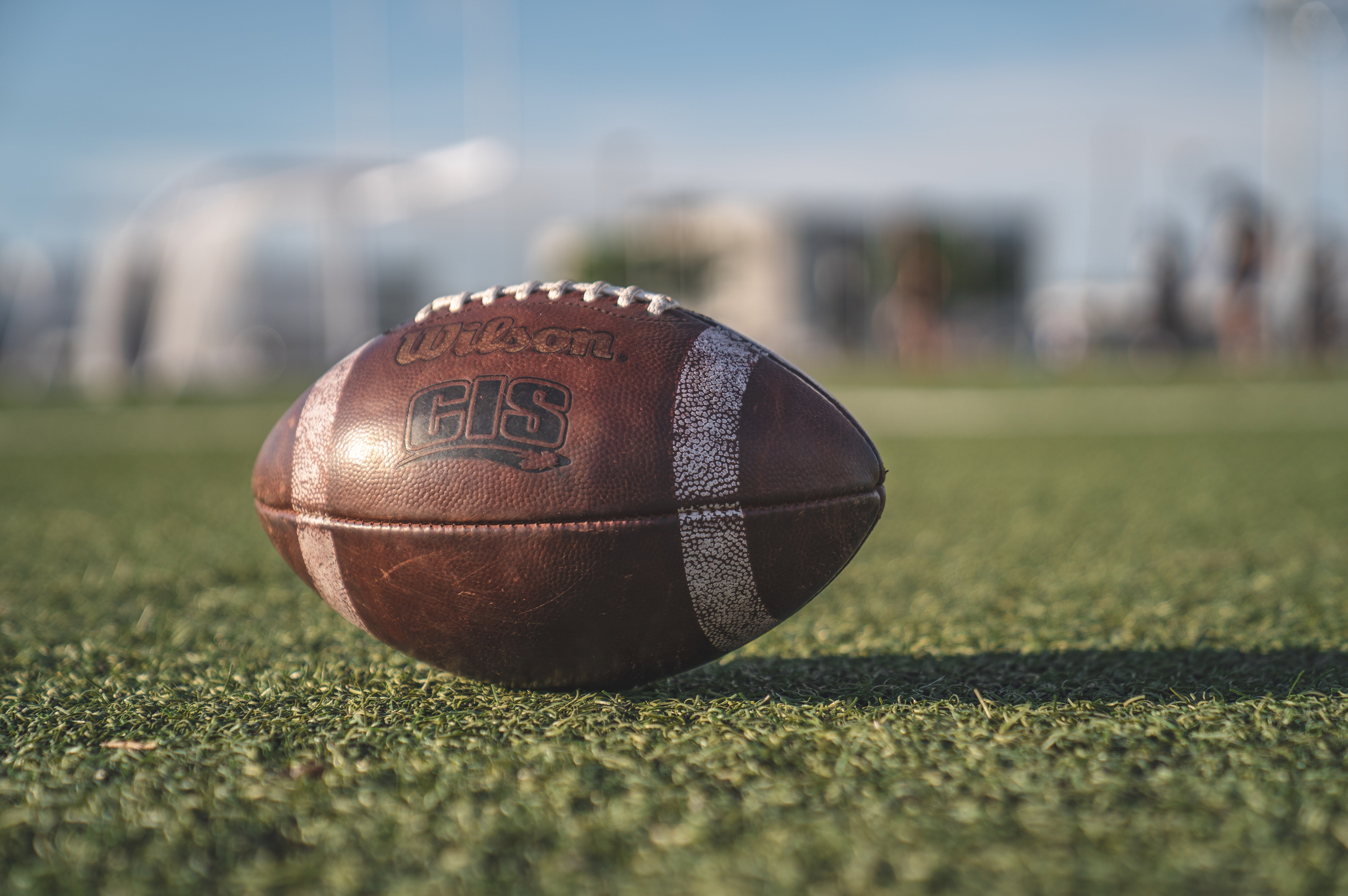 A brown football lying on a field. | Pexels/ Jean-Daniel Francoeur 