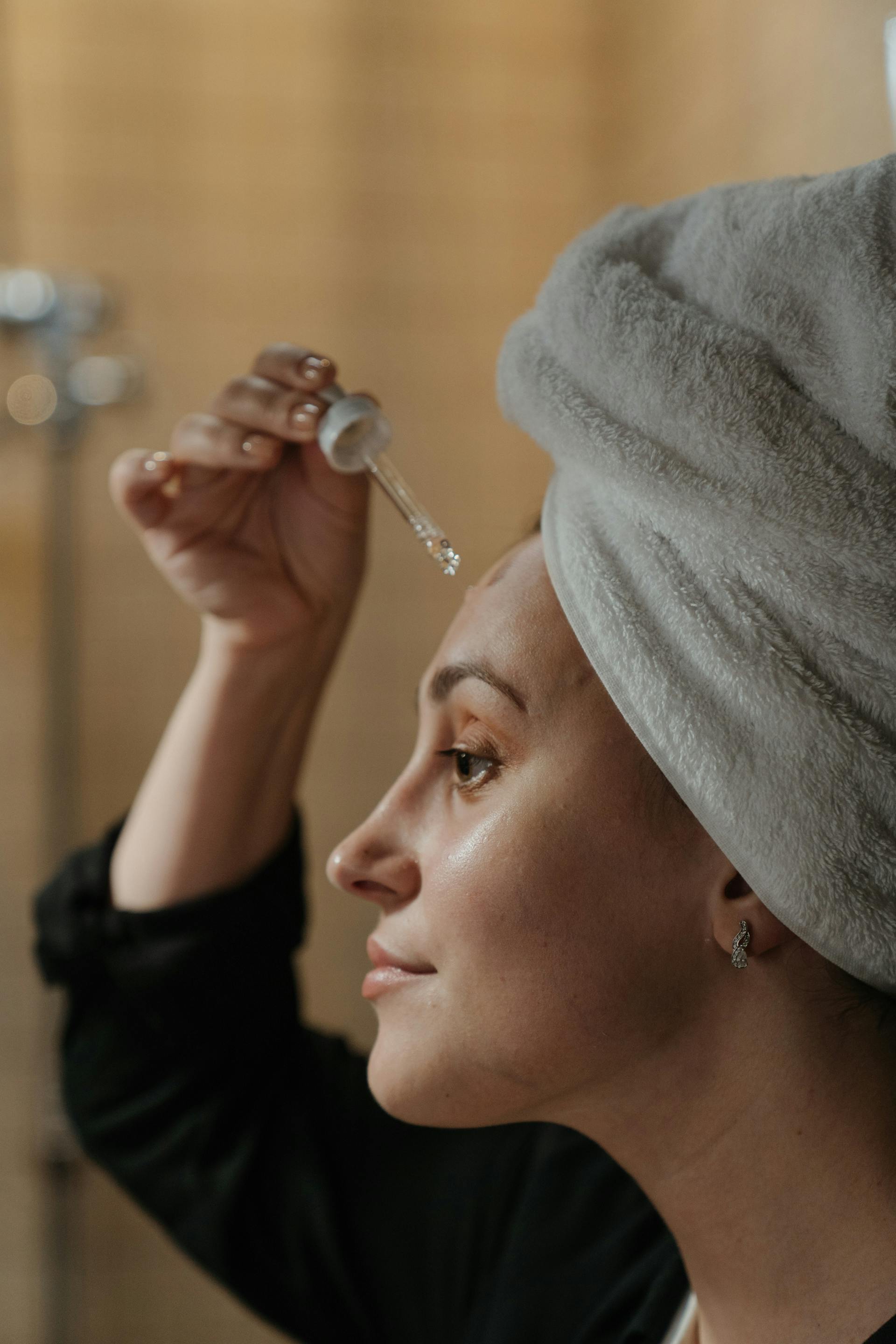 A woman applying a serum on her face with a dropper | Source: Pexels