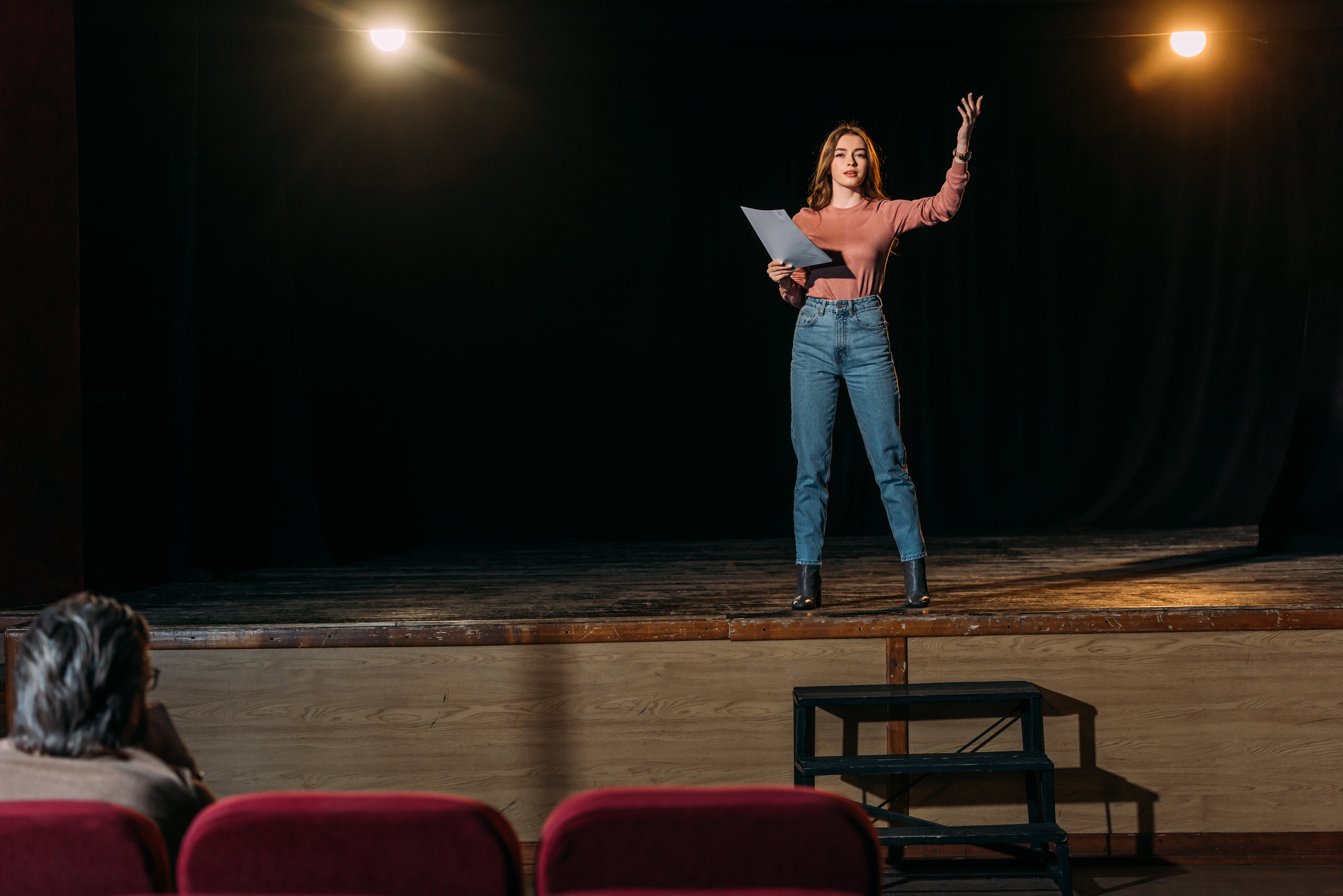 A woman on stage auditioning in front of a judge. | Source: Shutterstock