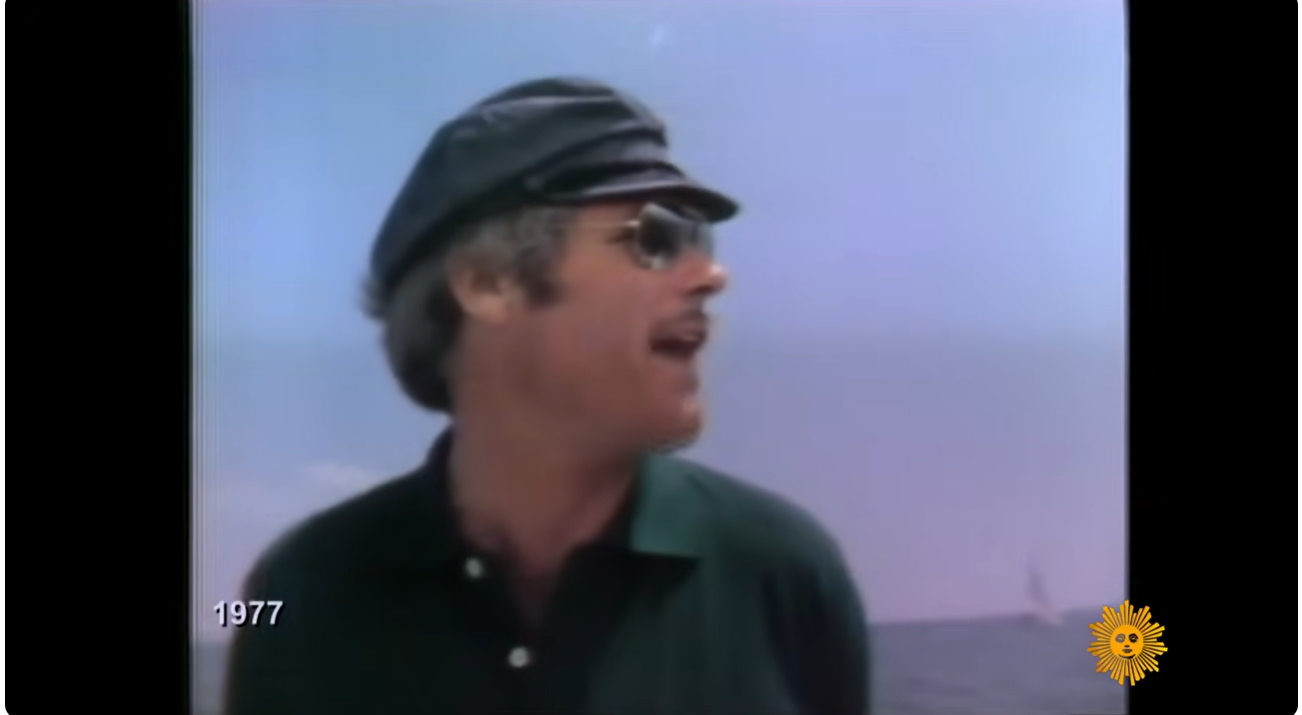 A young Ted Turner, wearing sunglasses and a captain’s cap in 1977, appears during the early years of the media empire that would later reshape cable television and sports broadcasting. | Source: YouTube/CBS Sunday Morning