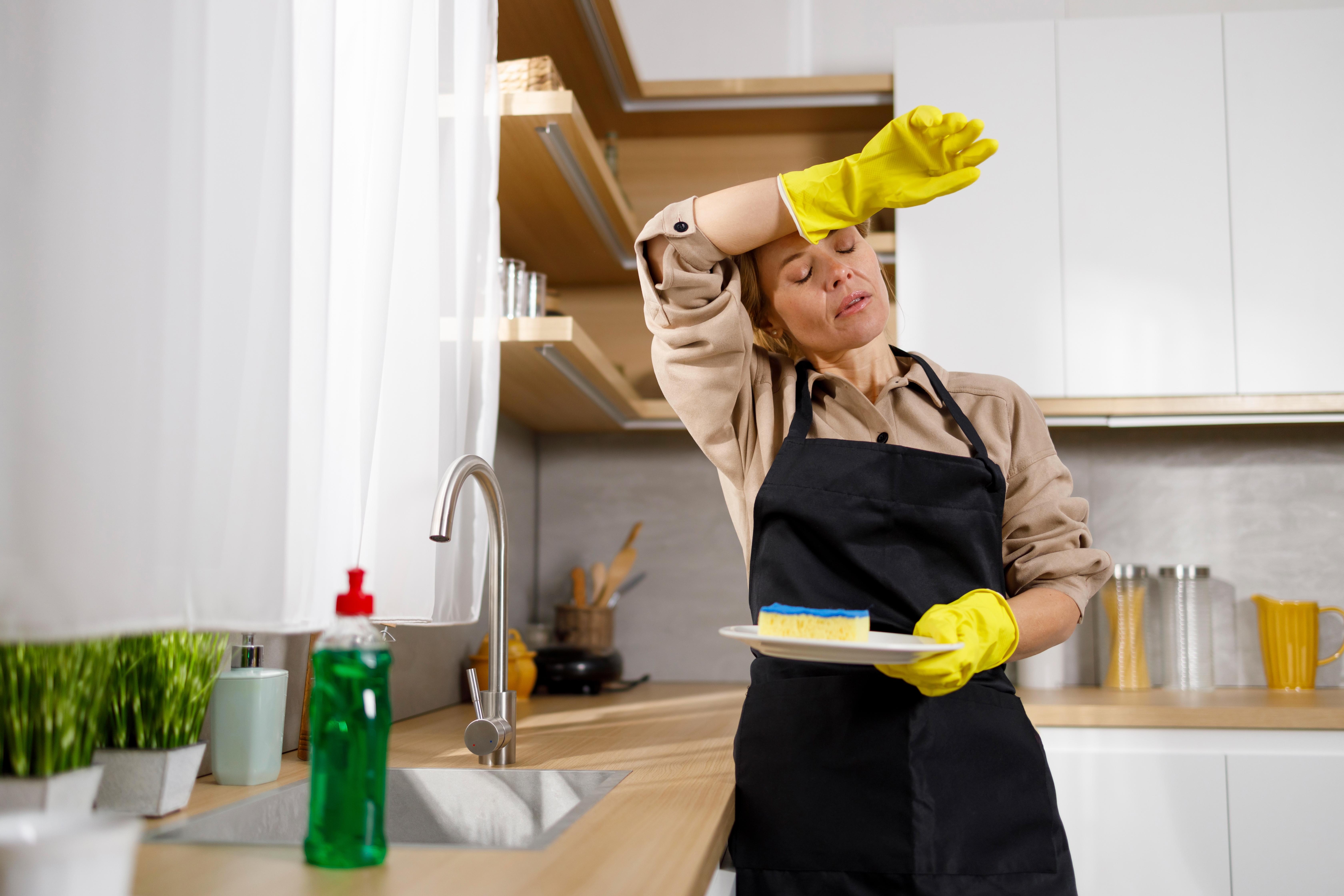 A tired woman washing dishes in the kitchen | Source: Shutterstock