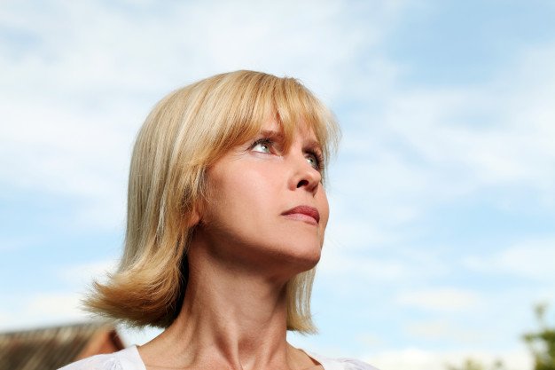 Perfil de una mujer rubia viendo hacia el cielo. | Foto: Freepik