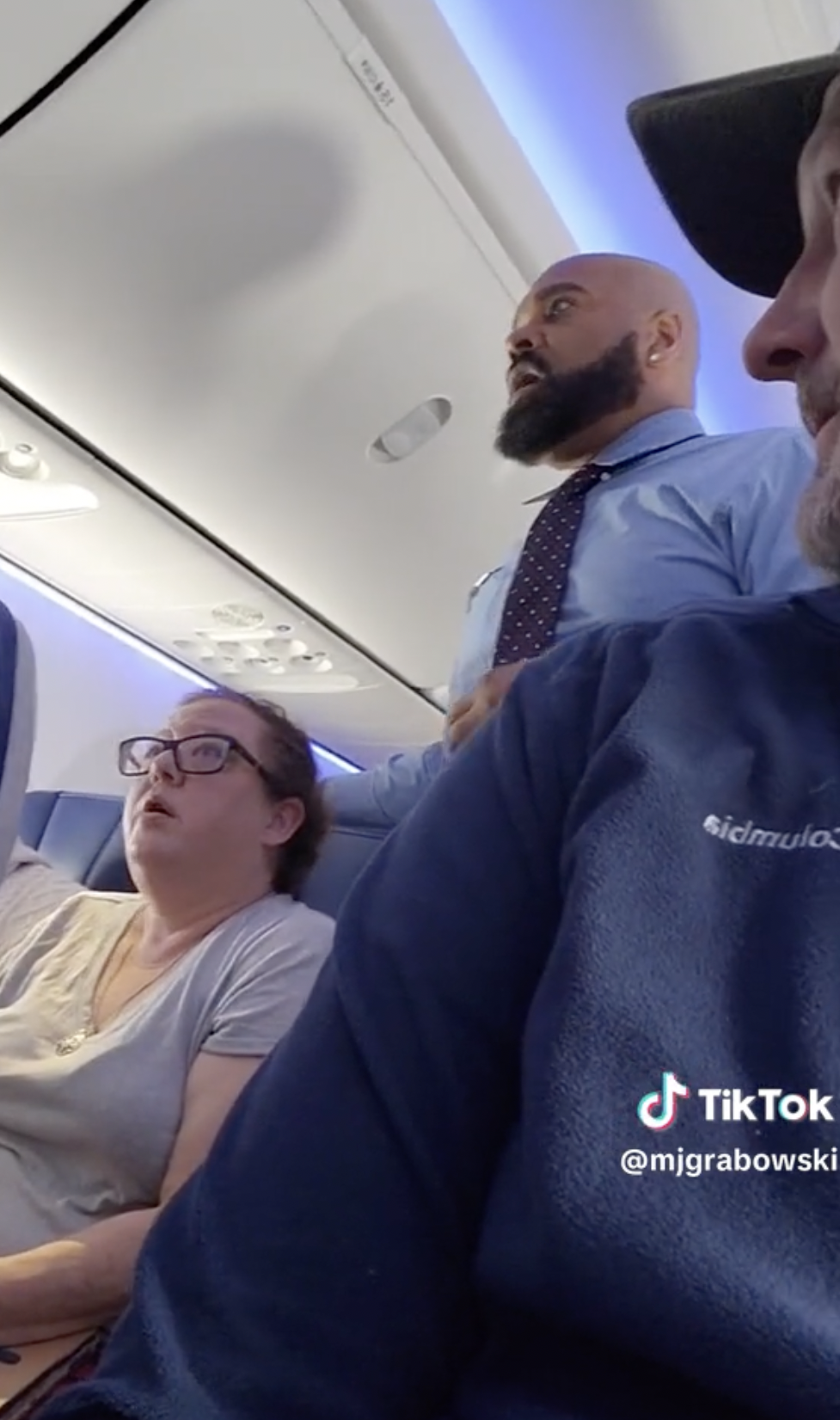Ein Mann amüsiert sich, während er einen wütenden Passagier aufnimmt, der sich über ein schreiendes Baby auf einem Southwest Airlines-Flug beschwert, während das Flugpersonal versucht, ihn zu beruhigen. Die Passagierin neben dem aufgebrachten Mann ist zu sehen | Quelle: TikTok/mjgrabowski