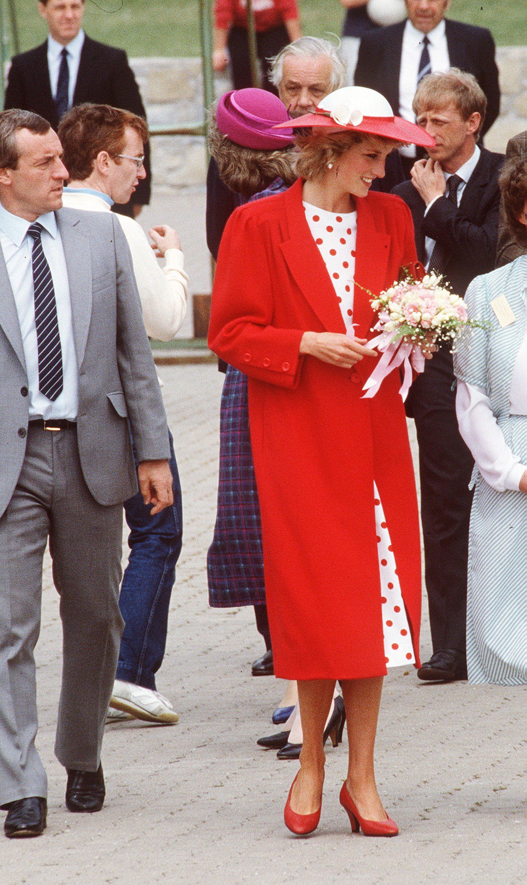  Diana, Princess of Wales, wearing a red jacket designed by Jan van Velden, with a white and red polka dot dress and a matching hat, with her bodyguard Barry Mannakee. | Source: Getty Images