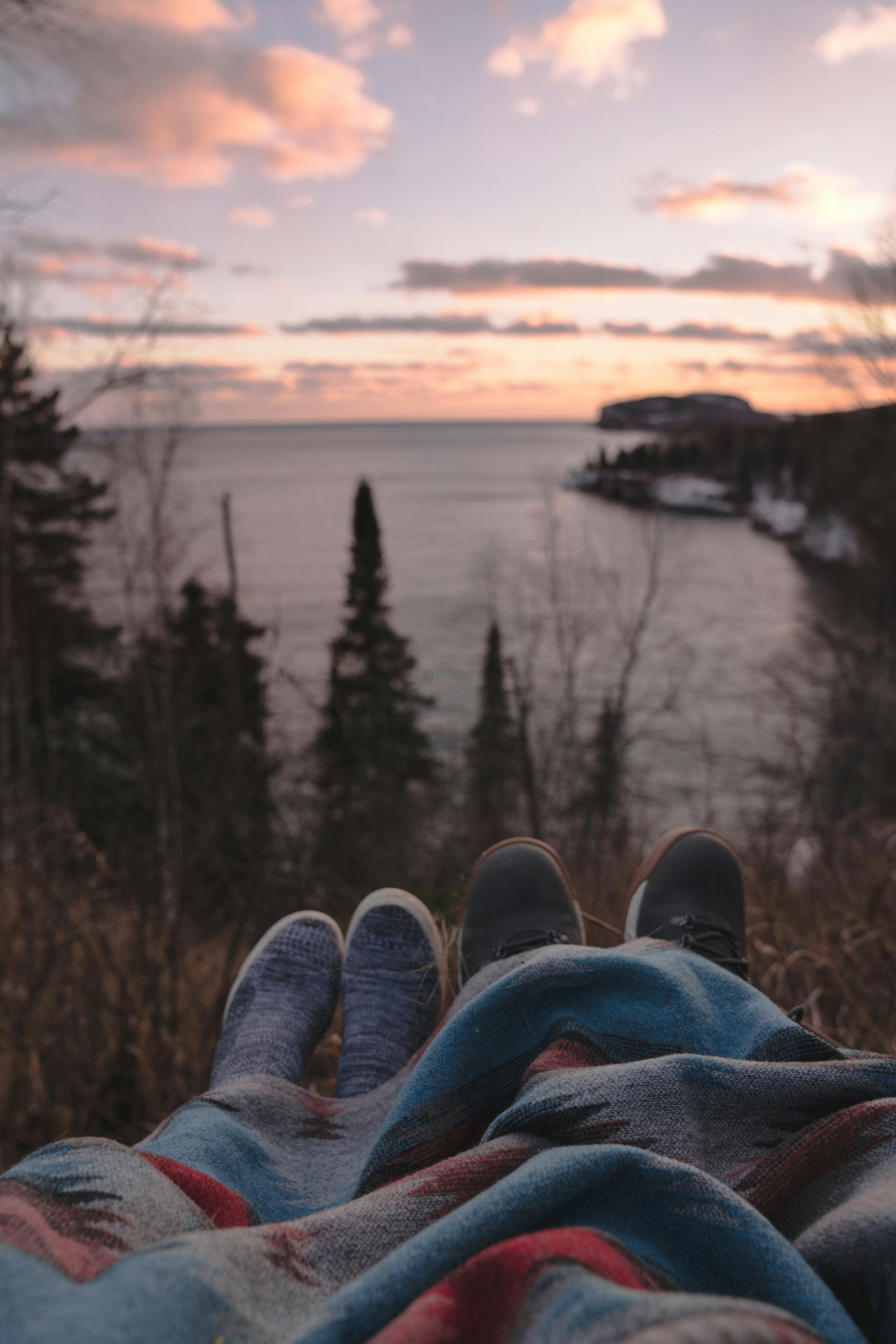 An anonymous couple lying on a hill at the seaside and enjoying the sunset | Source: Pexels