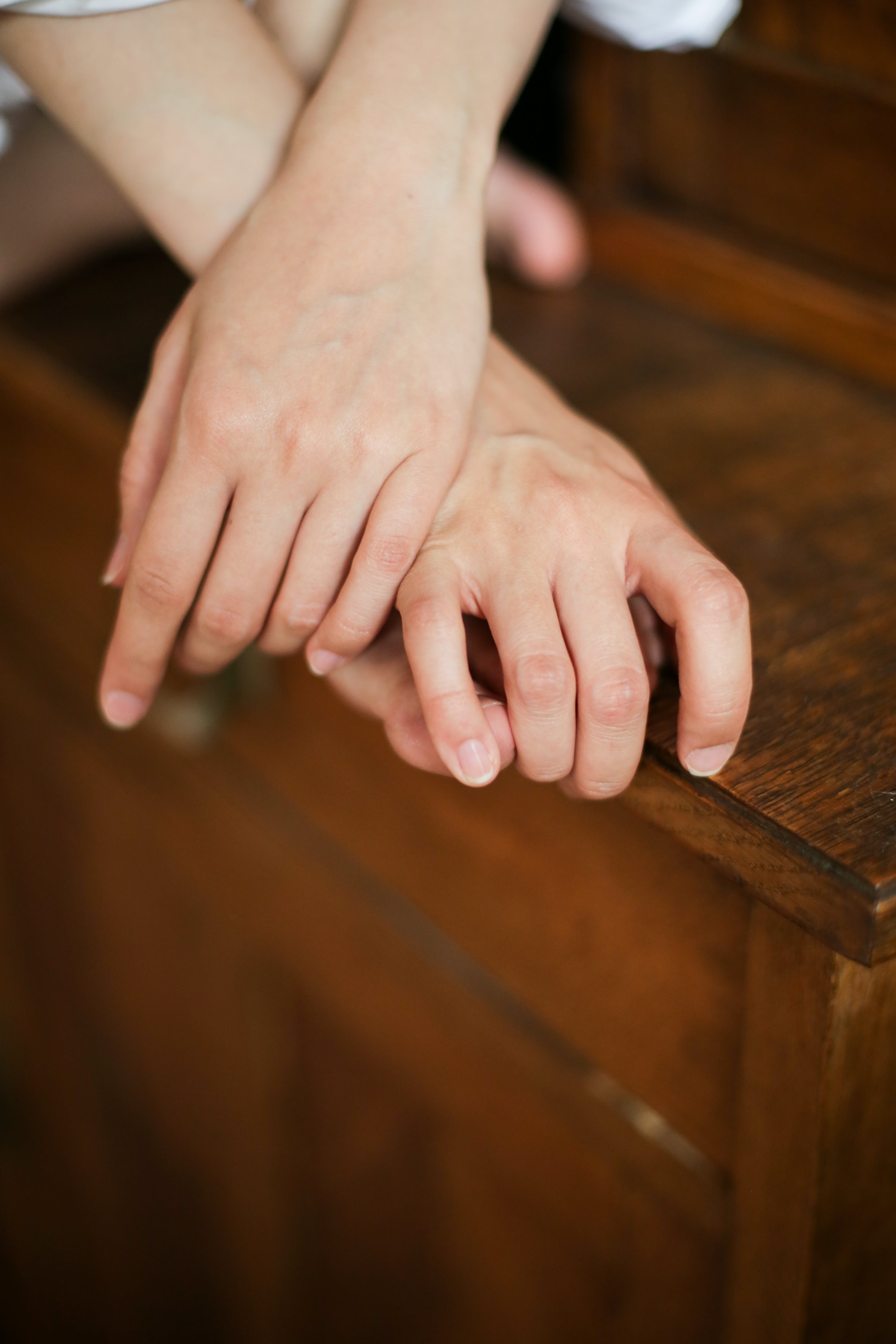 A person's hands on a wooden table. | Source: Pexels
