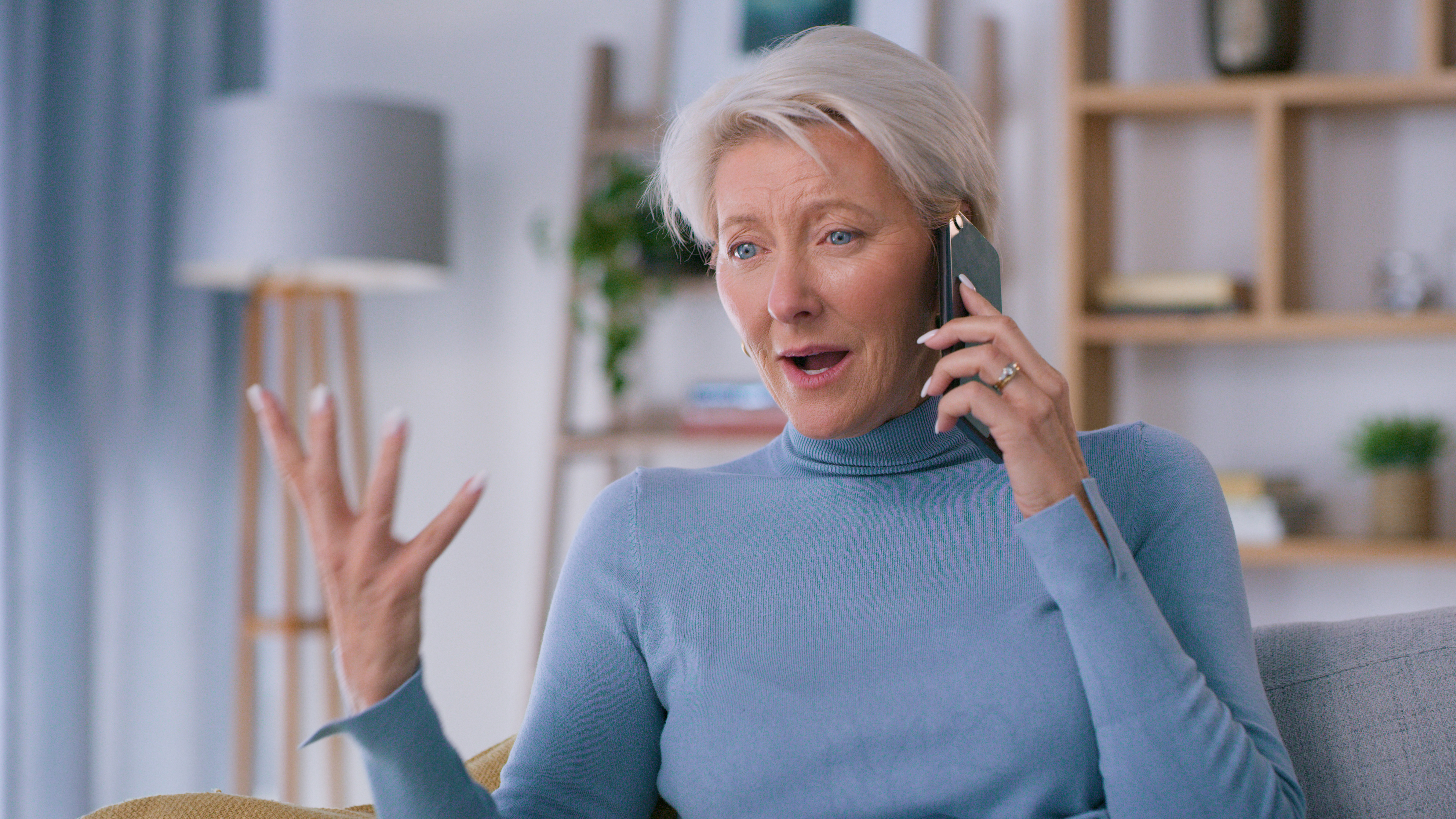 Frustrated senior woman, phone and discussion on house expenses, bills or financial crisis on sofa at home. Elderly female talking on smartphone in frustration for mortgage or bad news | Source: Getty Images