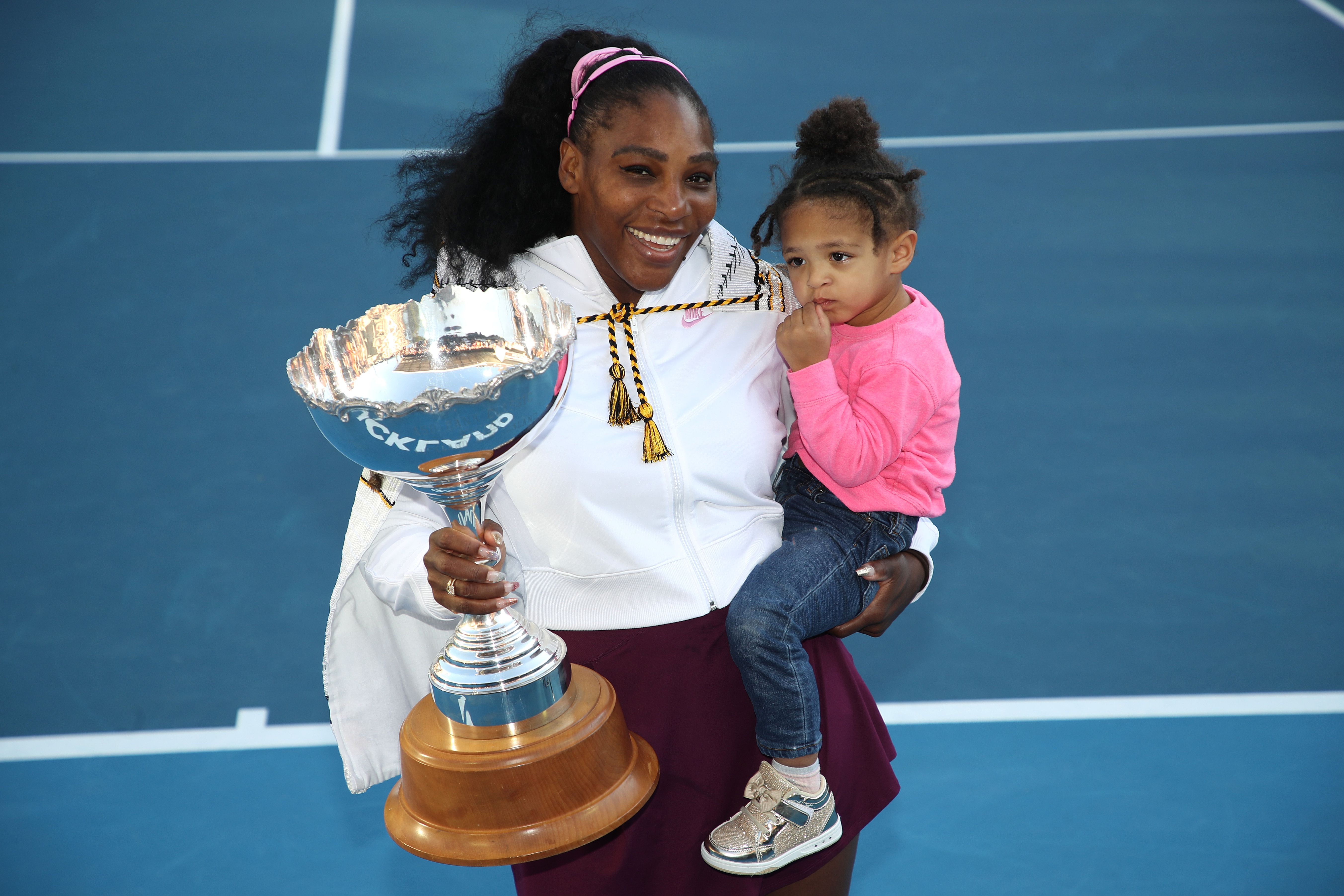 Serena Williams stood proudly holding her daughter, Alexis Olympia, during a trophy ceremony in January 2020, in Auckland, New Zealand. She wore a black long-sleeve top and a purple skirt as she shared the special moment on the court.