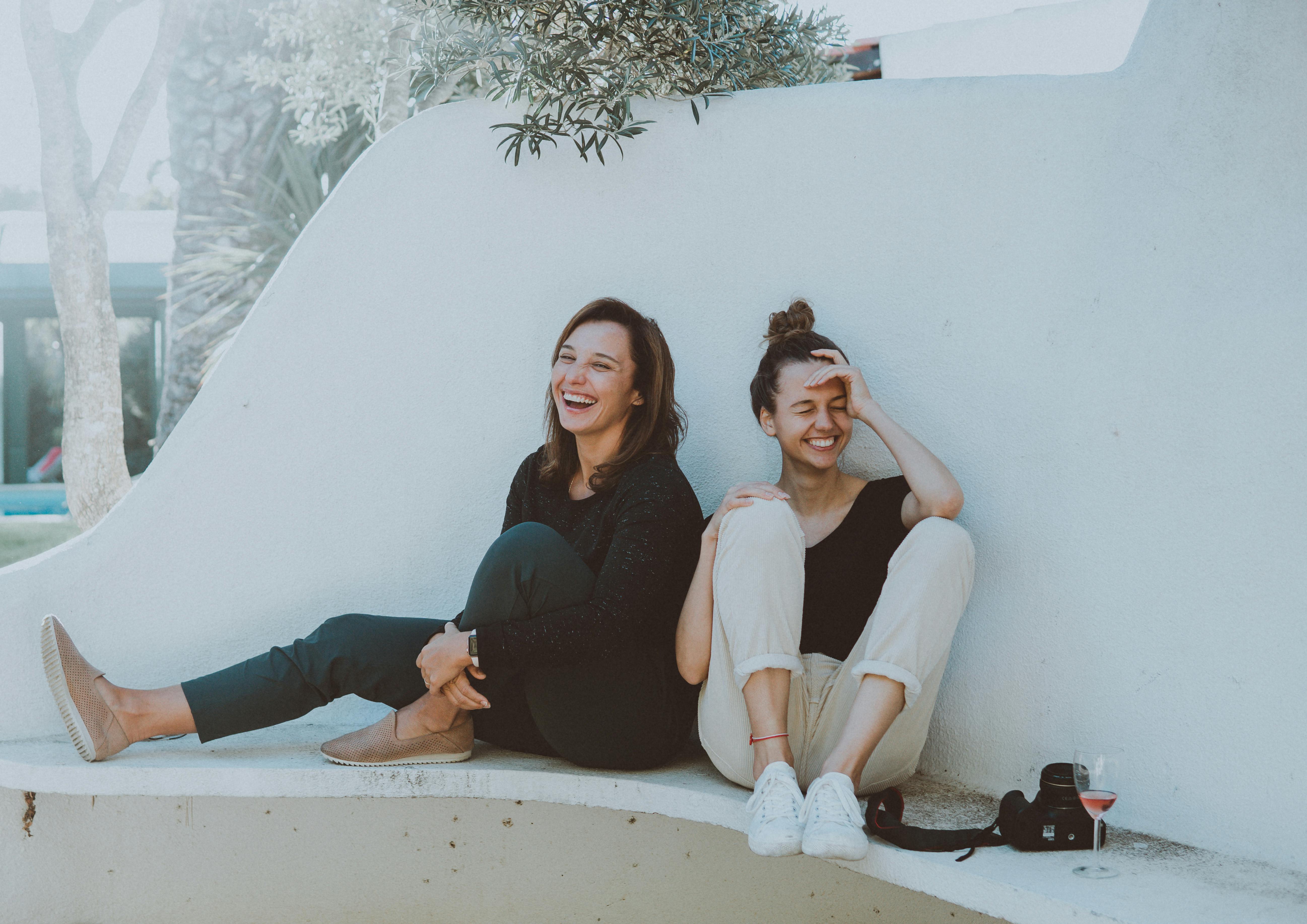 Two best friends sitting back to back and laughing | Source: Elle Hughes on Pexels