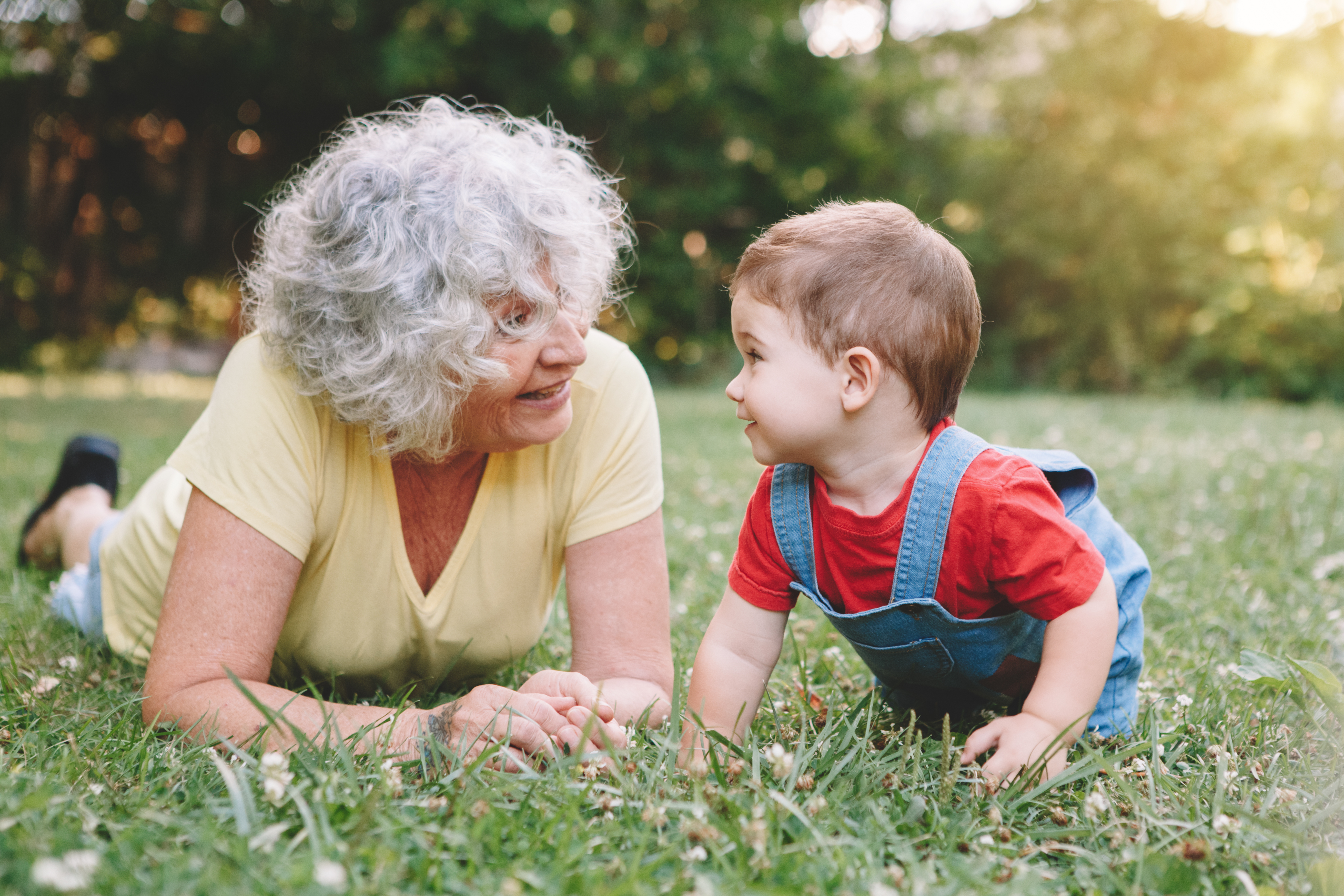 A grandmother and a grandchild laying in the grass | Source: Shutterstock