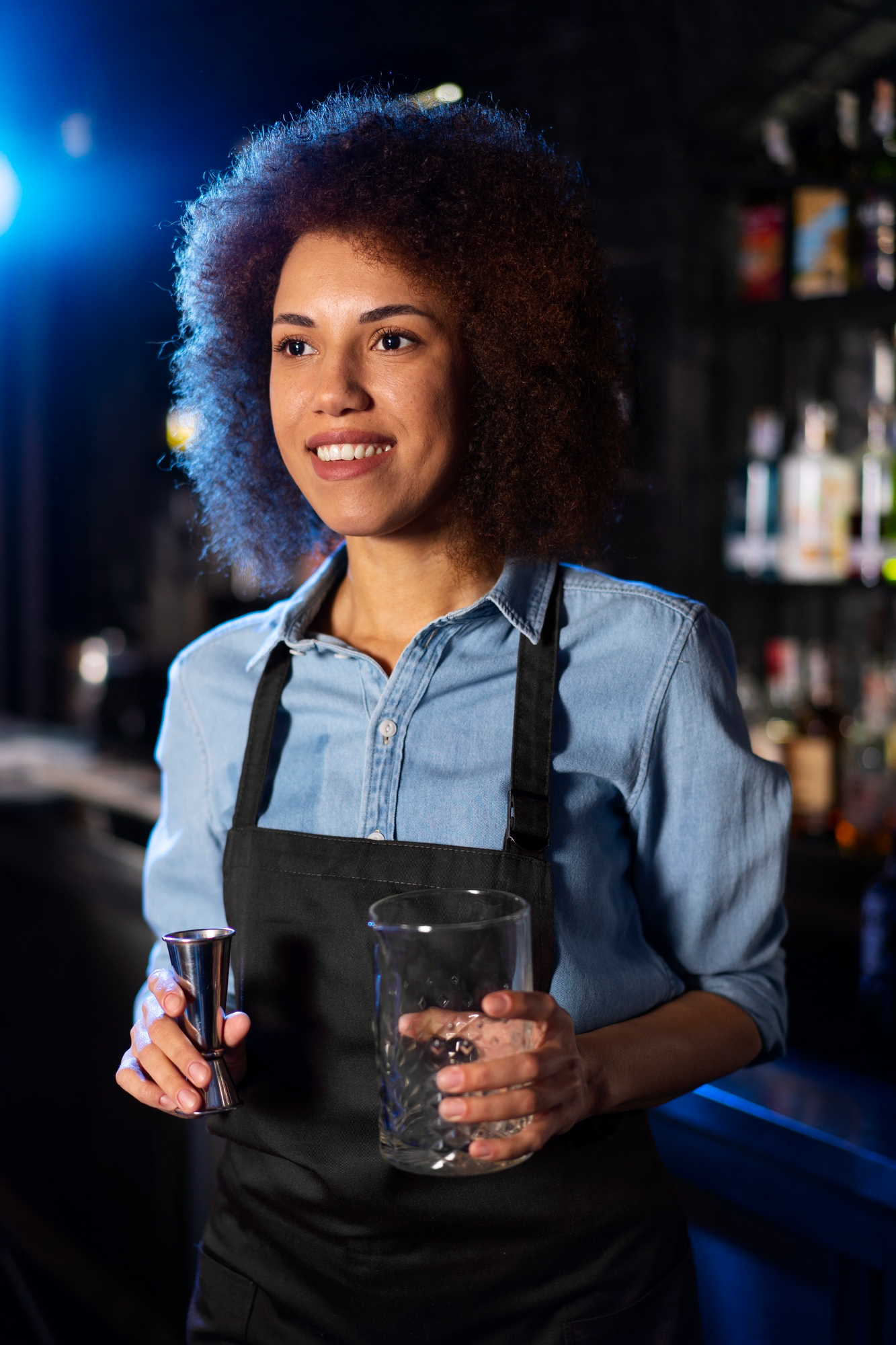 A happy waiter holding a glass and shot pourer for a drink | Source: Freepik