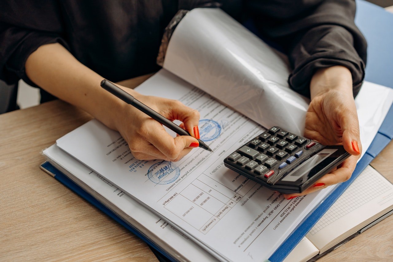 Mujer con una calculadora haciendo anotaciones en unos papeles. | Foto: Pexels